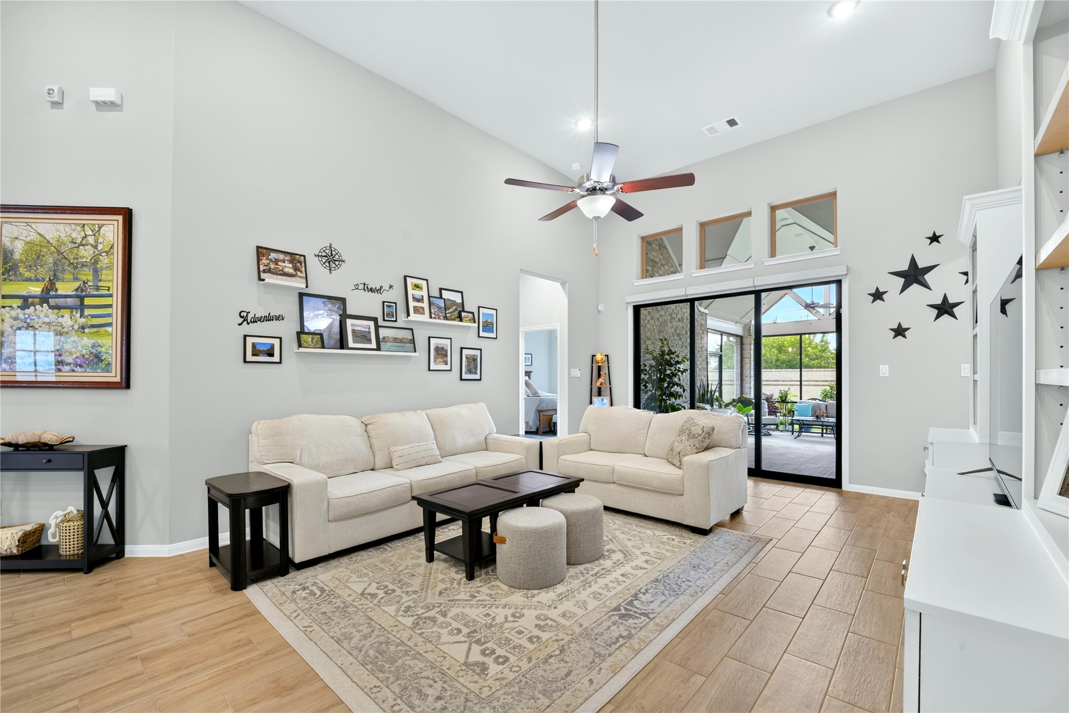 Bright and spacious living room featuring high ceilings, neutral paint, and tile flooring. Large sliding glass doors provide beautiful views of the covered patio.