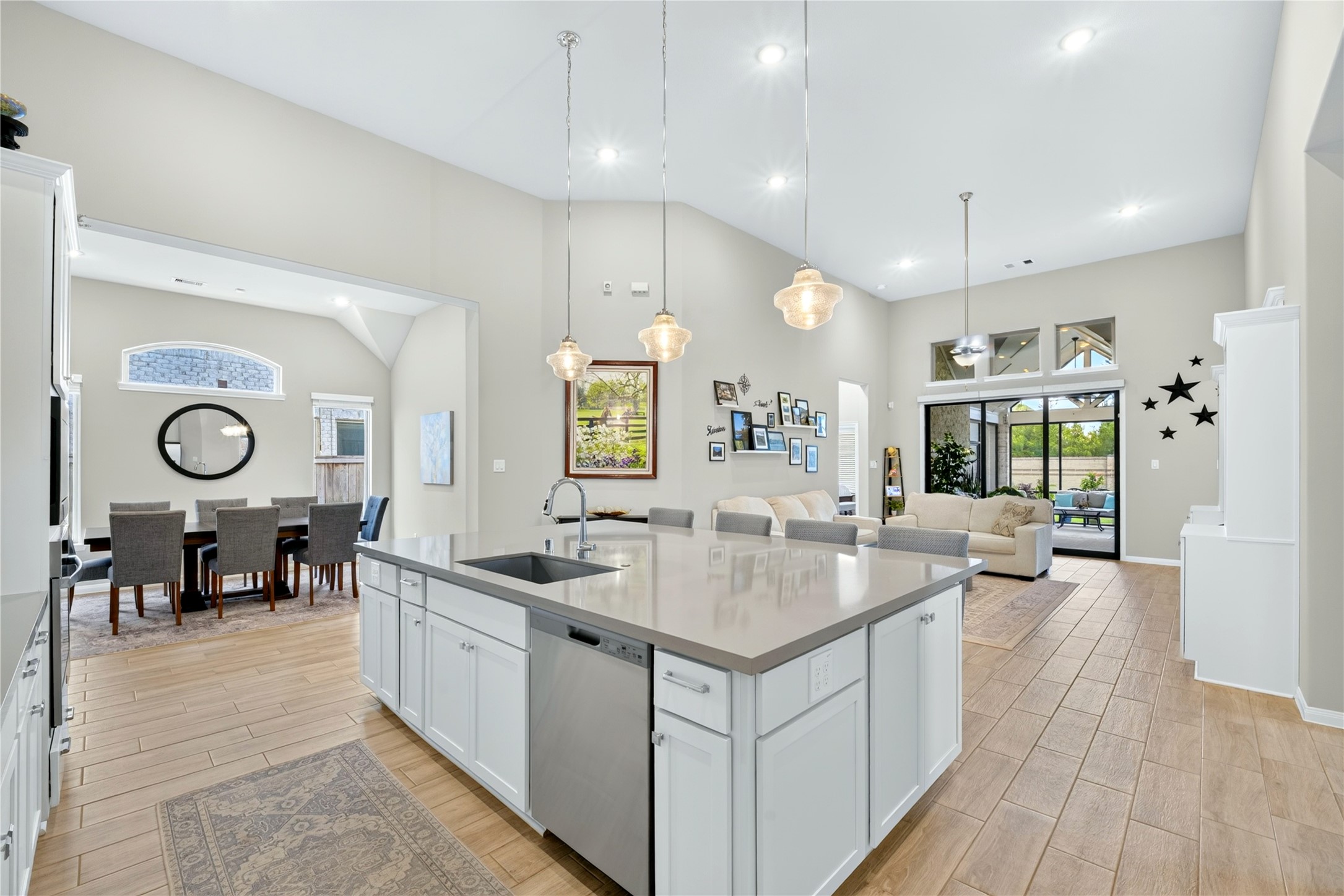 Beautifully designed Island Kitchen featuring an oversized granite countertop and soft neutral tones throughout. High Ceilings add airy, open feel, white cabinets surrounding the island including convenient pull out storage.