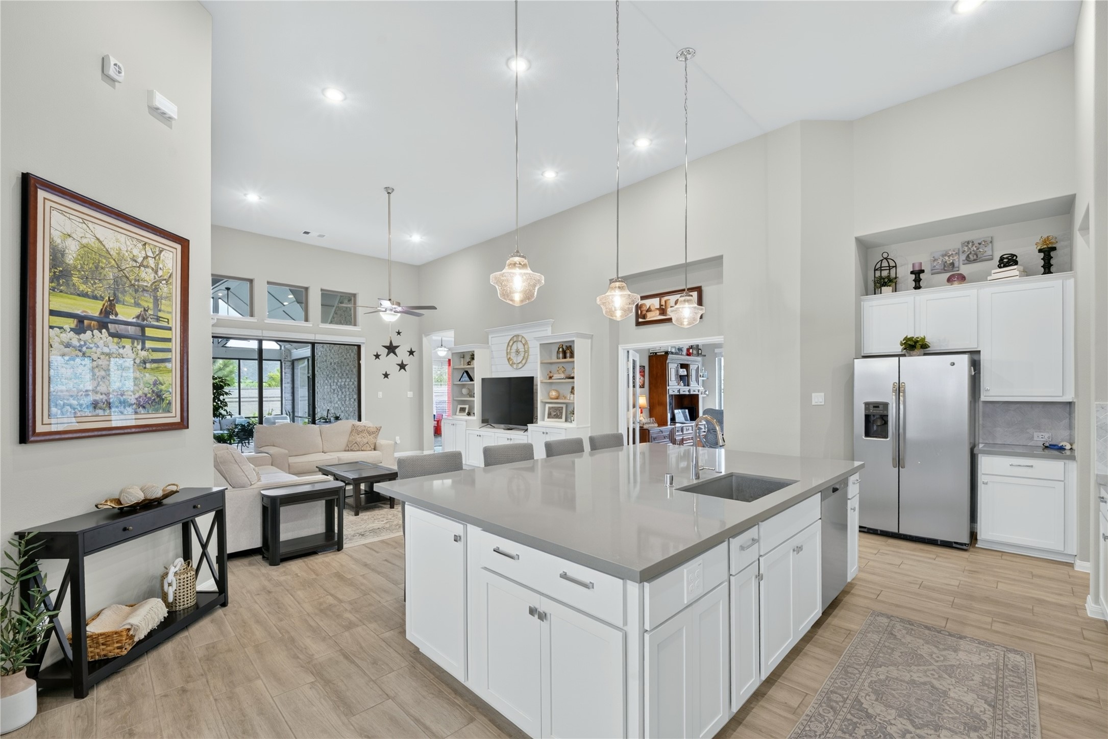 This beautifully oversized island kitchen is a chef's dream and an entertainer's delight. Crisp white cabinetry, elegant tile flooring, and soaring ceilings create a bright, open feel, while direct views to the covered outdoor patio keep space connected to the beauty just beyond the doors.