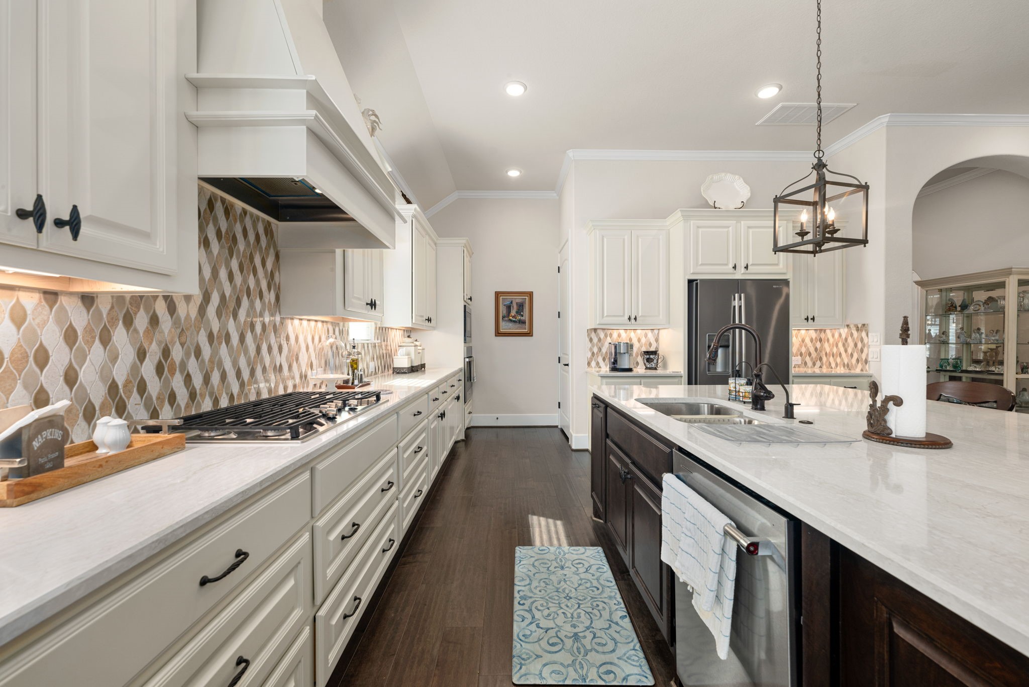 Every detail shines in this gorgeous kitchen! Featuring a gas cooktop, designer backsplash, beautiful quartz countertops, abundant cabinetry, and an oversized island with a double sink and stainless steel dishwasher!