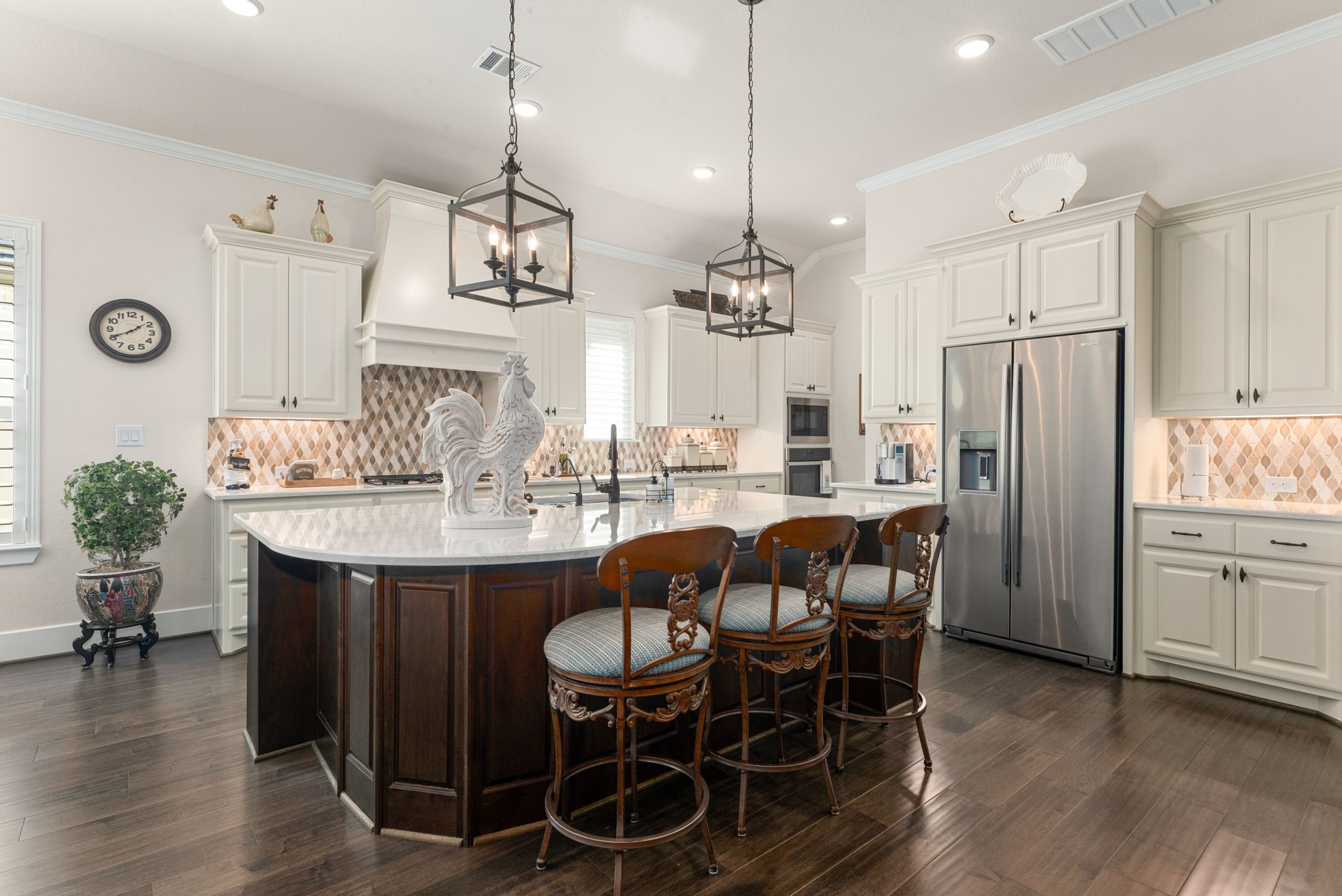 A kitchen designed to impress! Featuring a spacious island with gorgeous quartz countertops, designer backsplash, custom cabinetry, stainless steel appliances, and stunning pendant lighting. Perfect for cooking, gathering, and entertaining!