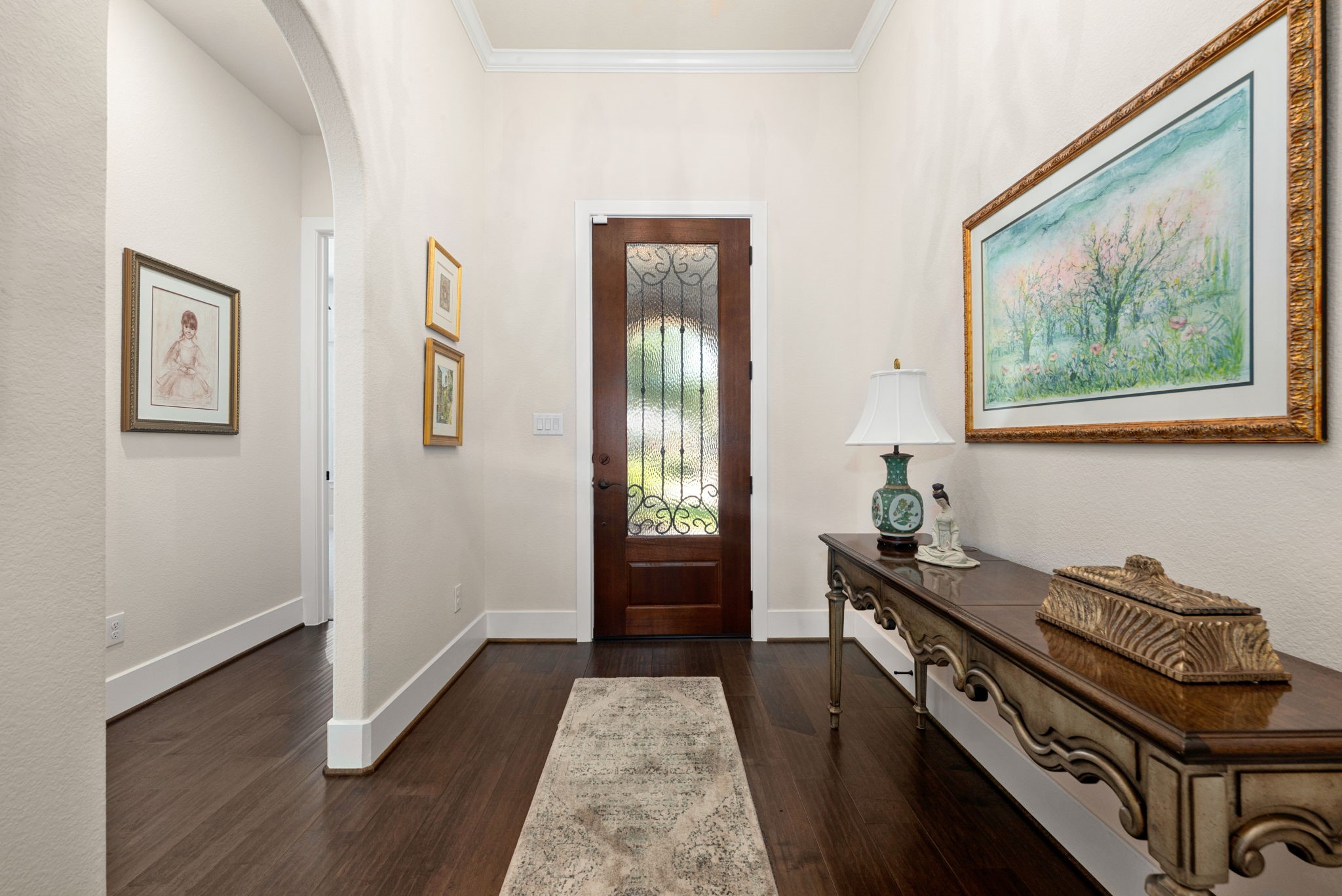 A warm welcome awaits! This inviting entryway features beautiful wood flooring, elegant crown molding, and a graceful arched opening that sets the tone for the rest of the home.
