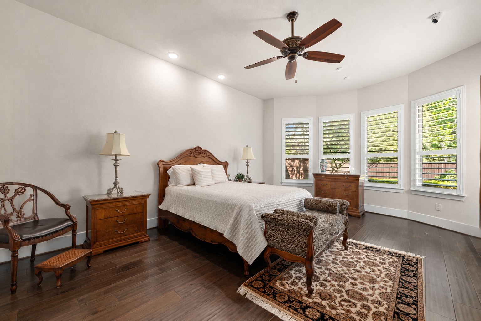 Welcome to your beautiful primary suite! This spacious retreat offers gorgeous wood flooring, elegant shutters, abundant natural light, and plenty of room for a comfortable sitting area.