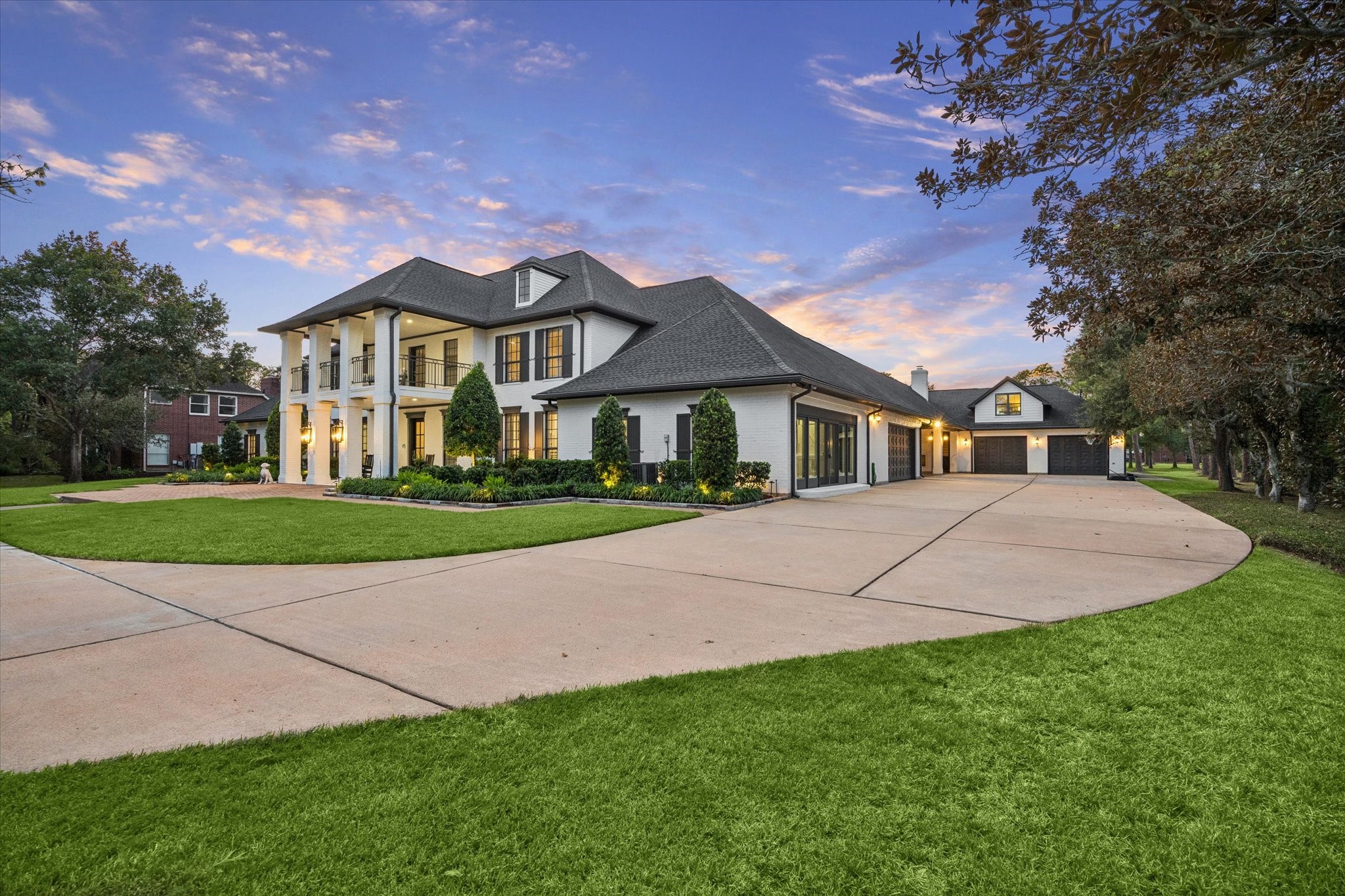 The Samson Custom home has been meticulously updated in 2018 with timeless and elegant finishes. Stately two-story home with grand columns, expansive driveway, and manicured lawn set against a picturesque sunset backdrop.