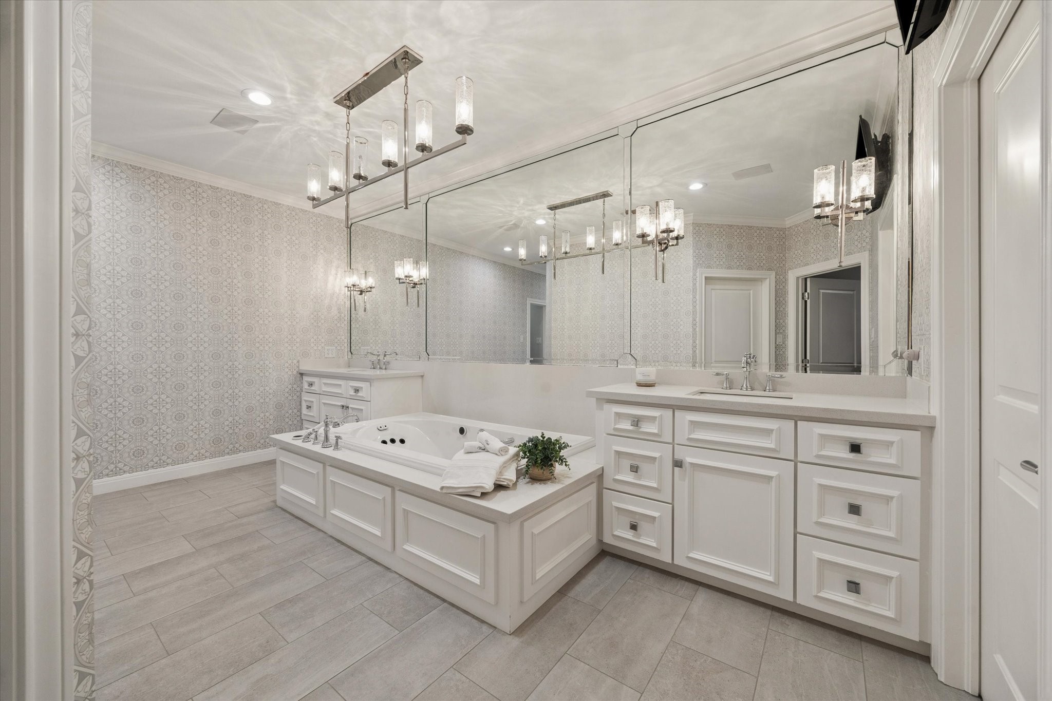 Second floor primary bath featuring a jetted soaking tub, elegant custom wallpaper, and dual walk-in closets.