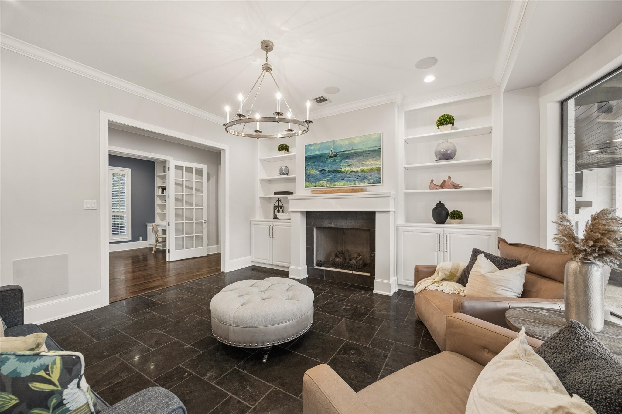 Spacious living room featuring a gas log fireplace, custom built-in cabinetry, and expansive floor-to-ceiling windows offering an unobstructed view of the backyard oasis.