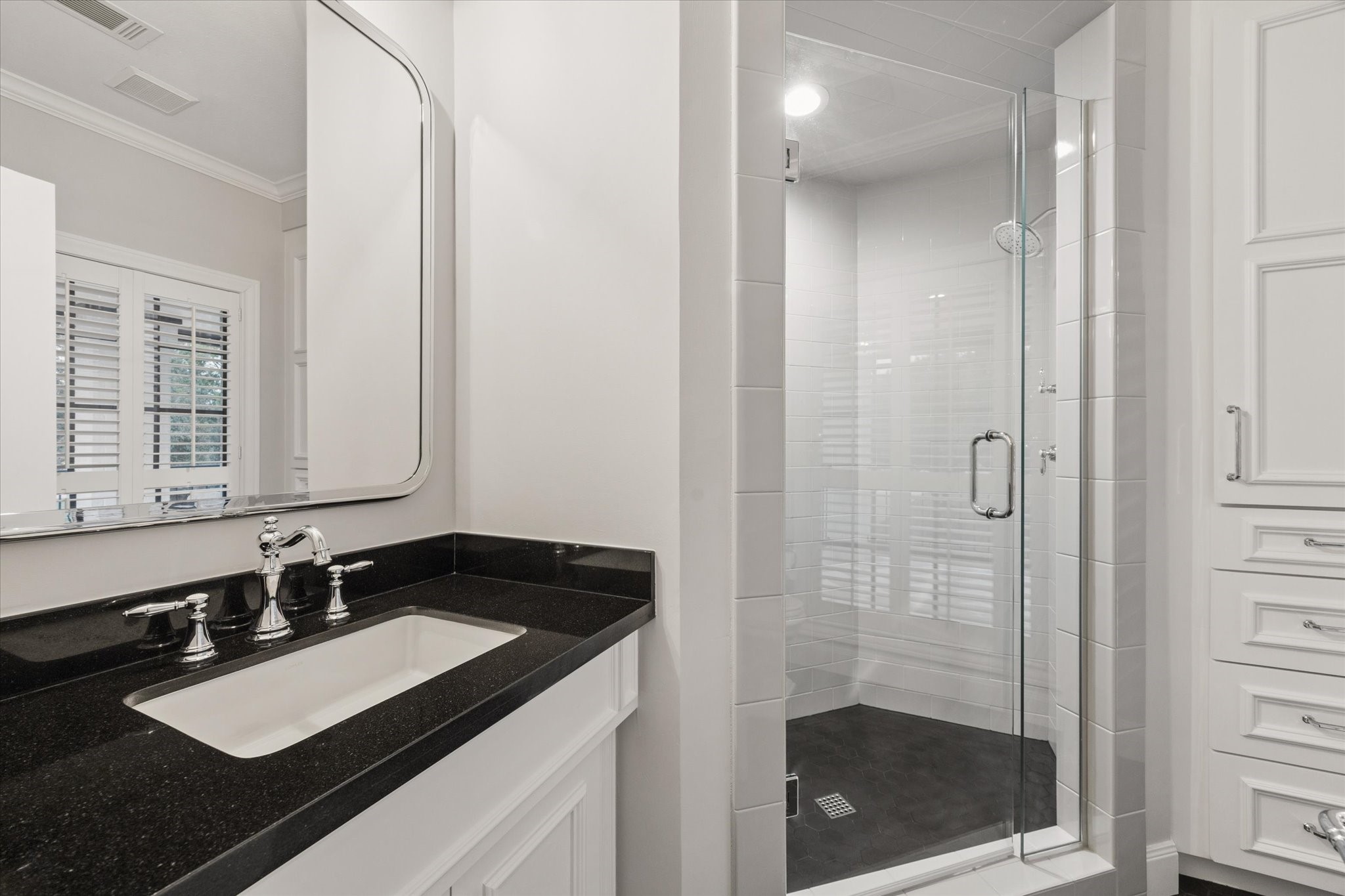 Elegant bathroom with a sleek black countertop, modern fixtures, and a spacious glass-enclosed shower for a luxurious experience.