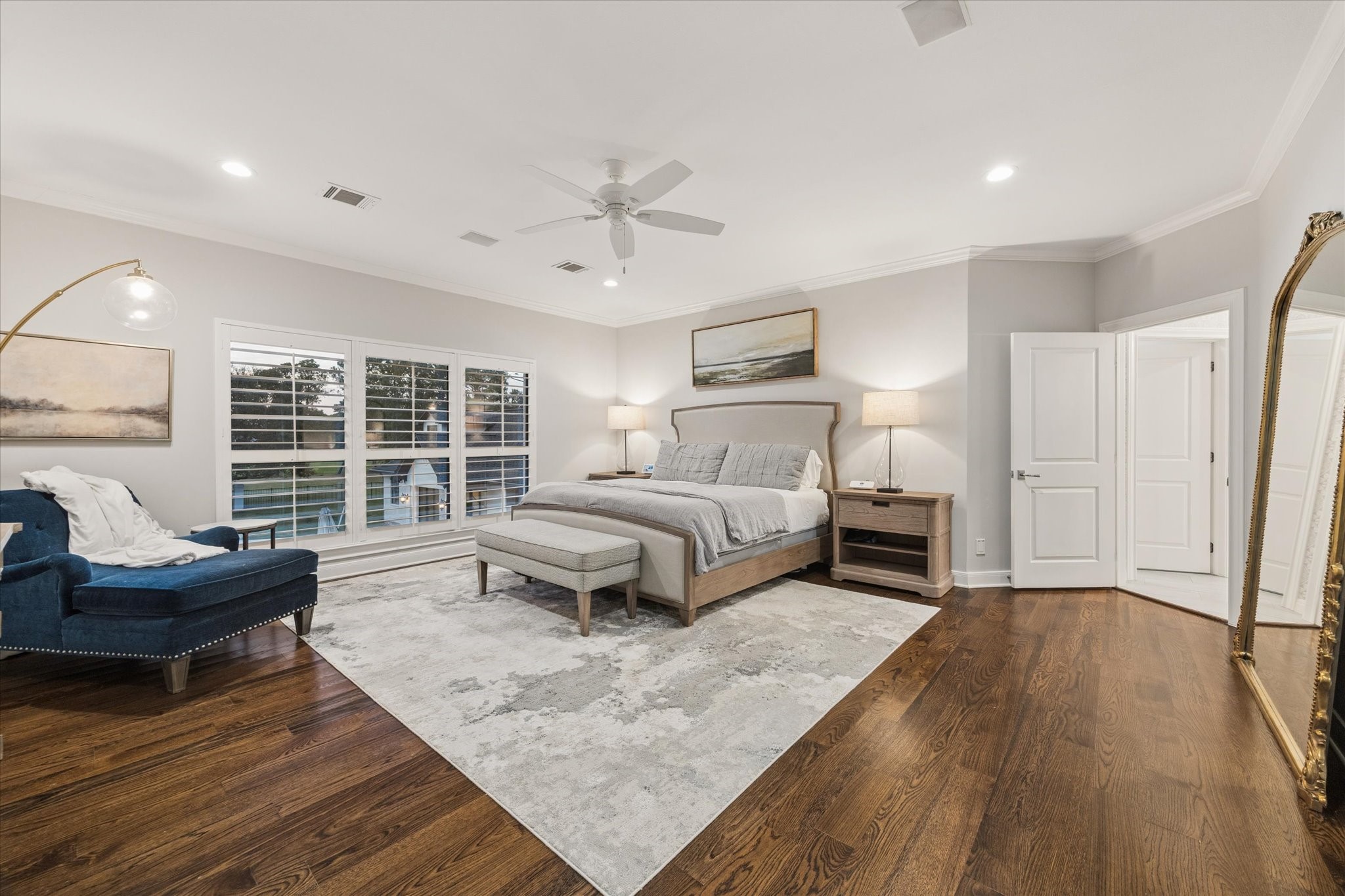 Second-floor primary bedroom featuring a scenic view of the backyard, rich hardwood flooring, and a spacious ensuite bathroom.