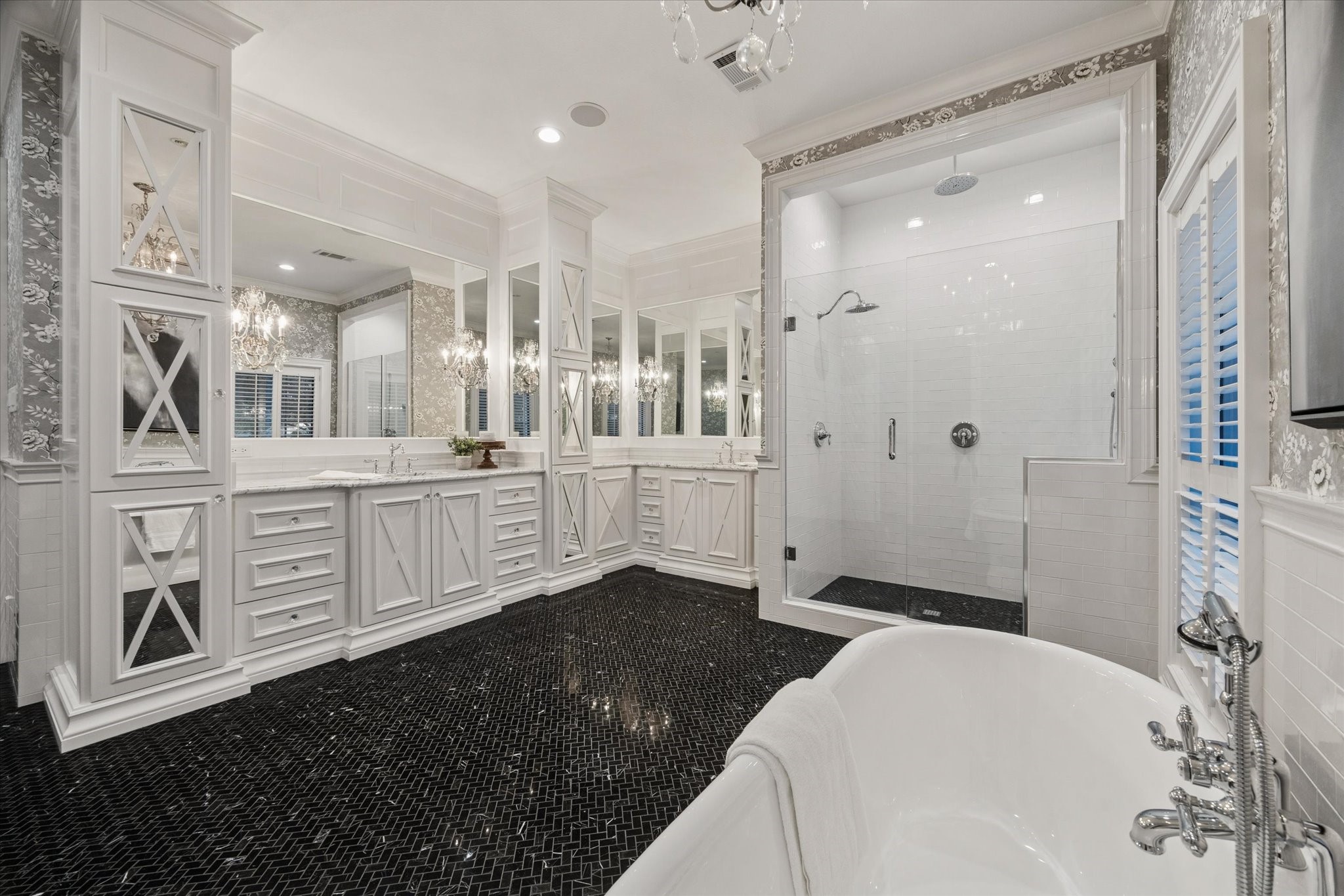 Elegant primary bathroom on the first floor featuring mirror-beveled cabinetry, a separate shower, a soaking tub, and generous storage space.
