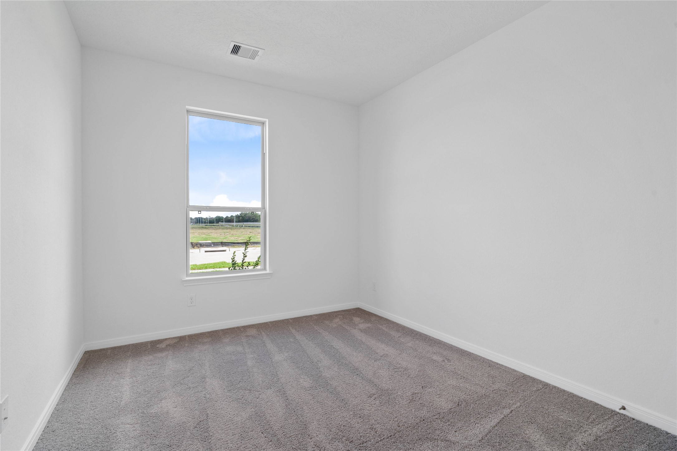 Located in the front of the home, this secondary bedroom offers comfort and style with plush carpeting, neutral paint tones, recessed lighting, a large window, and closet.