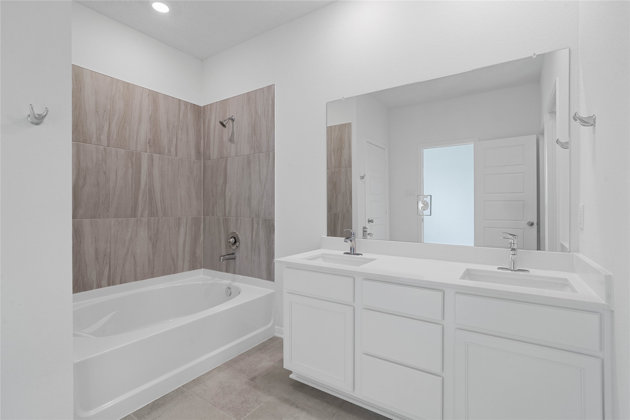 This primary bathroom is definitely move-in ready! Featuring dual sinks, white stained cabinets with light countertops, mirror, high ceilings, neutral paint, tub/shower combination with tile surround, sleek fixtures, and modern finishes.