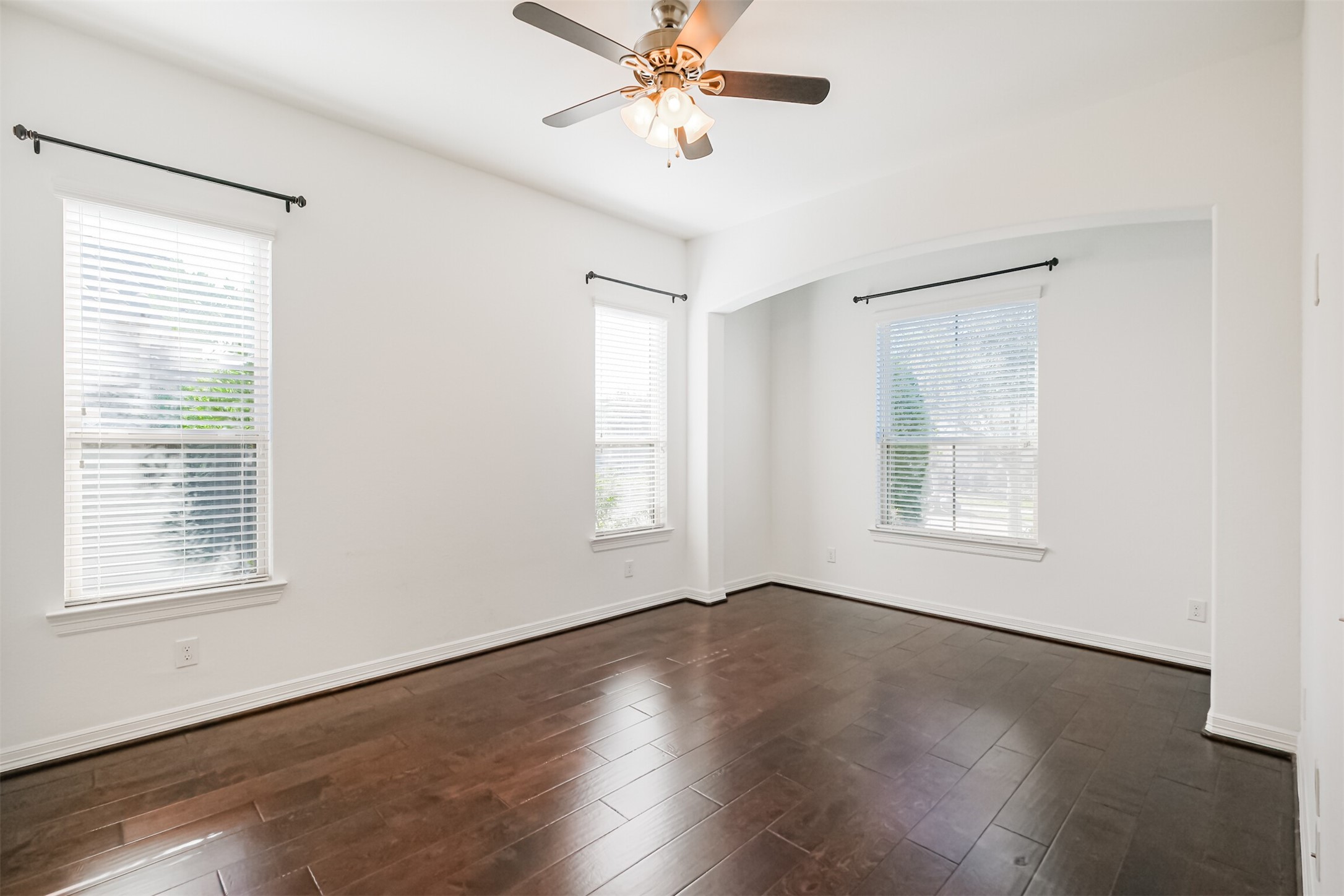 The room is full of natural light from the three large picture windows.
