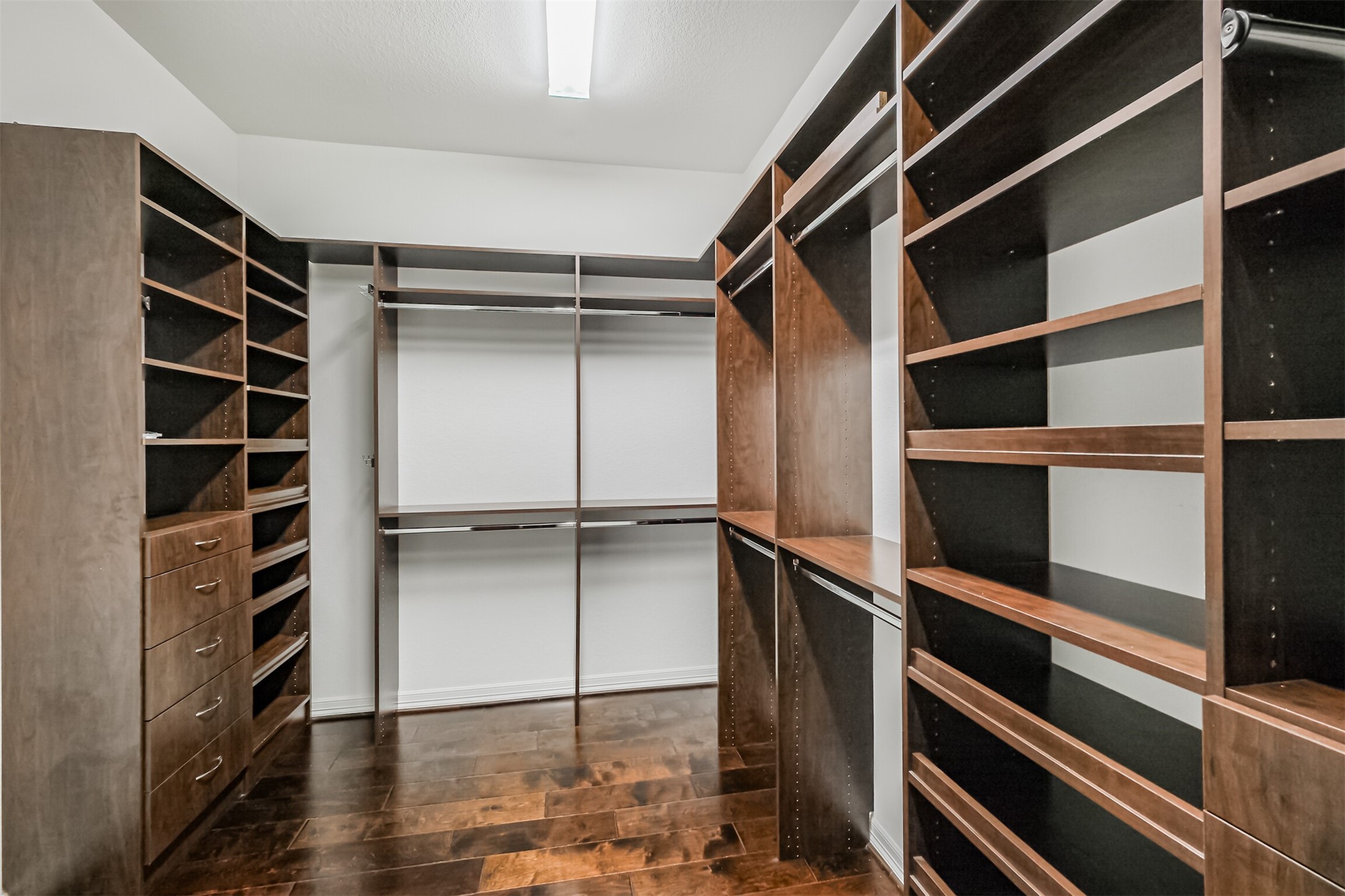 Well-designed built-in primary closet with shelving, drawers, and hanging racks.