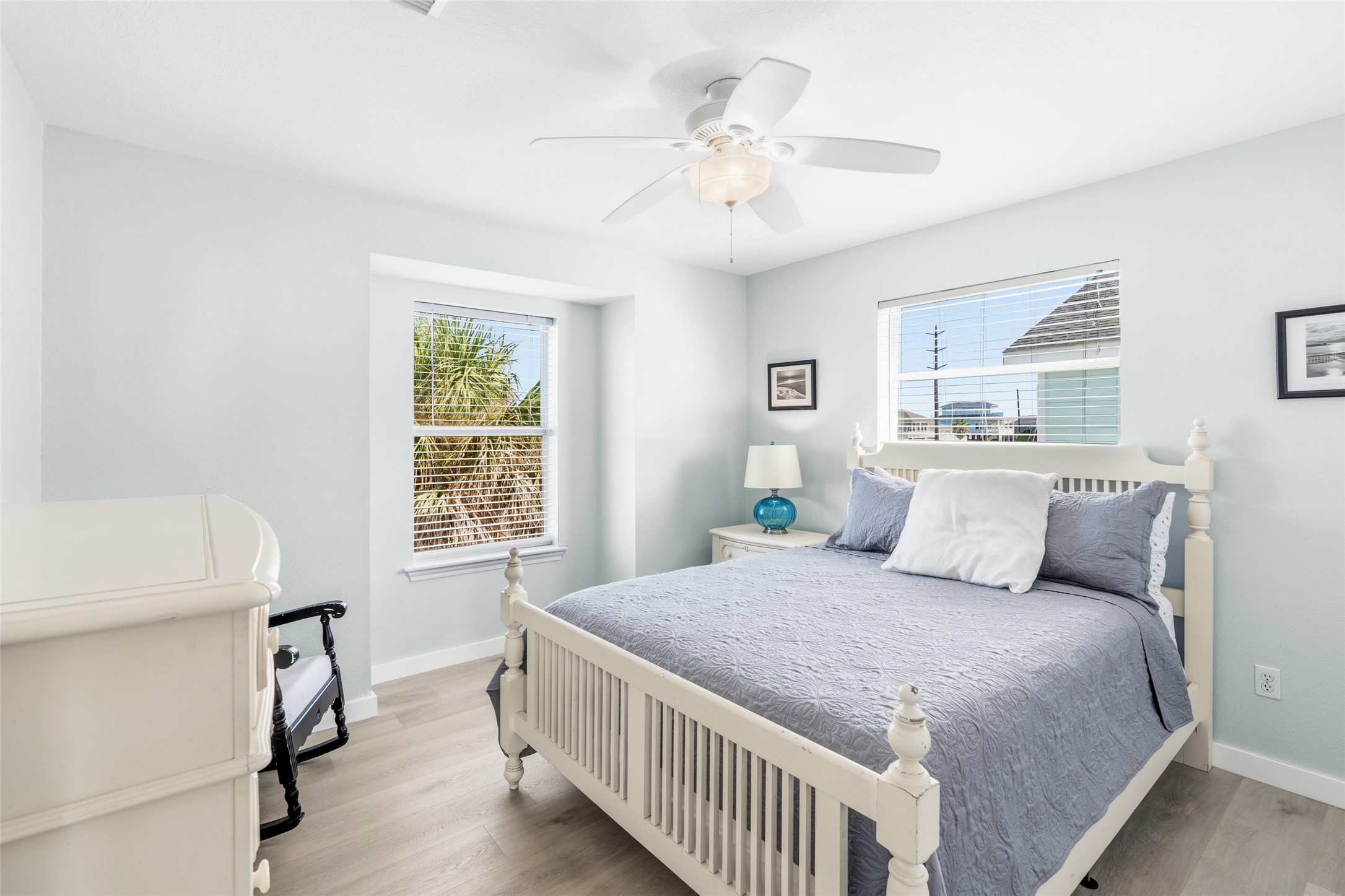 Bright and inviting bedroom features a ceiling fan and ample natural light from two windows.