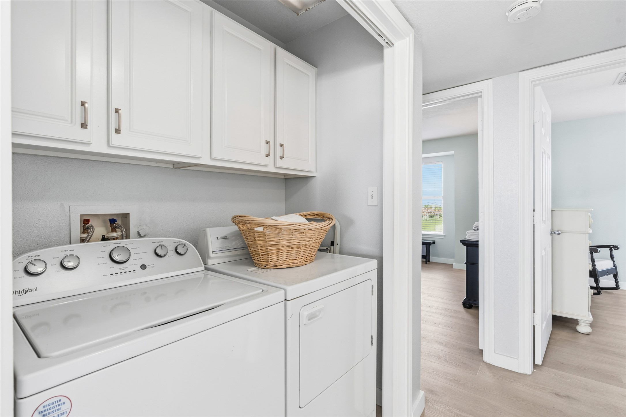 Convenient laundry area with a washer and dryer, ample cabinets for storage, and easy access to adjacent rooms.