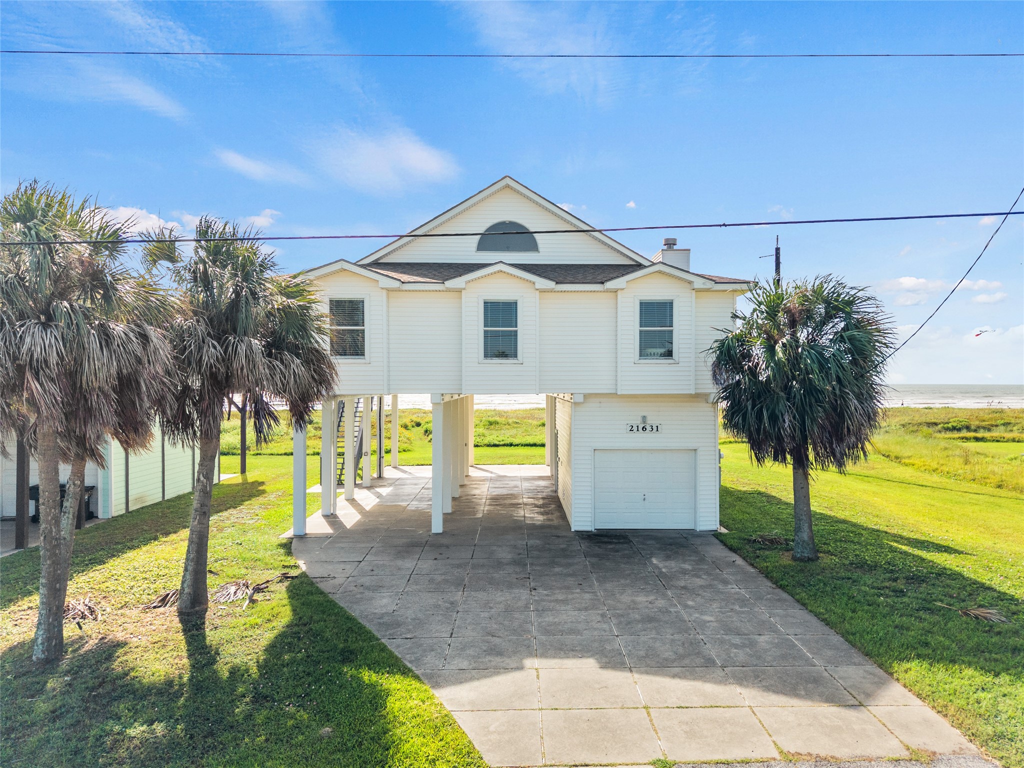 Coastal home with ocean views features a spacious driveway and lush palm trees. Coastal home with ocean views features a spacious driveway and lush palm trees.