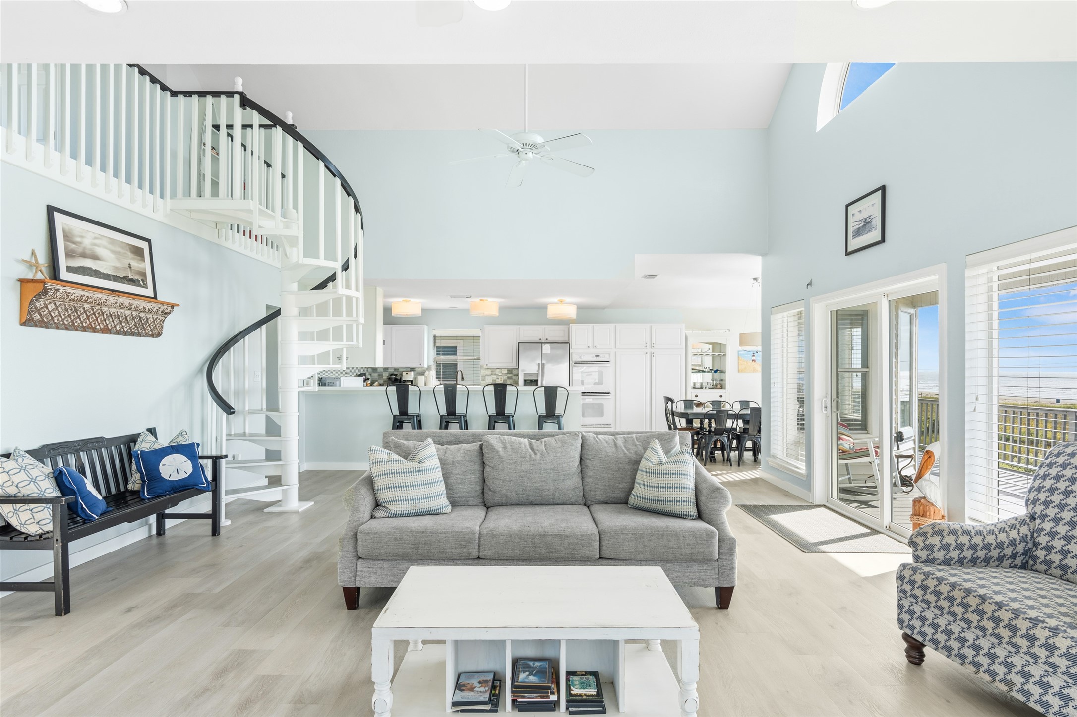 Bright and airy living space with a spiral staircase, and an open-concept layout, featuring a cozy seating area and open to the kitchen with bar seating.