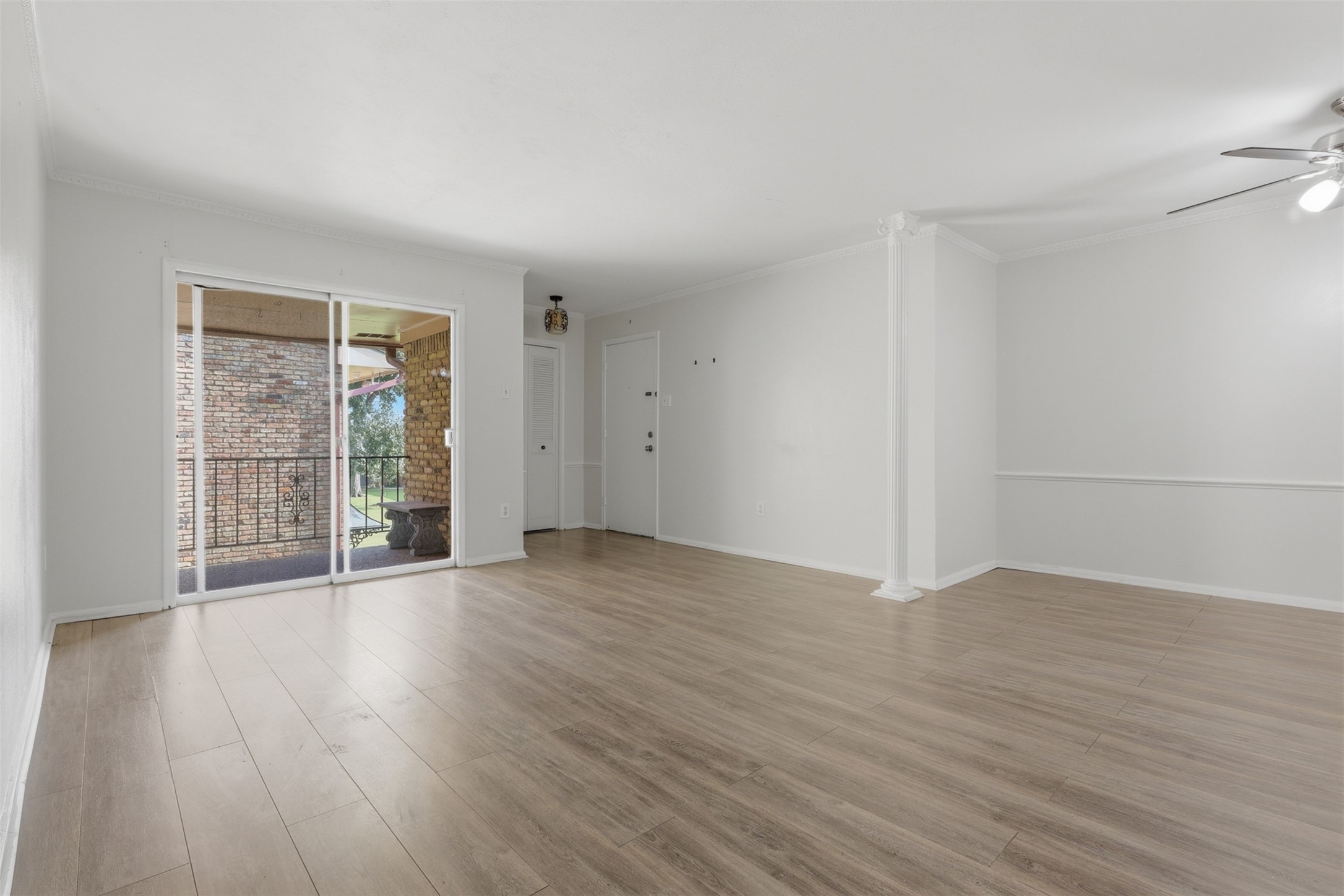 Bright and inviting living space with sleek wood floors, abundant natural light, and seamless access to a charming outdoor balcony.