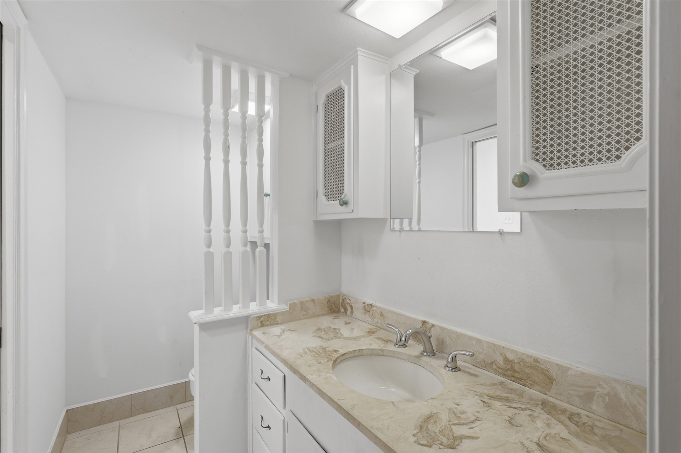 Elegant half bathroom featuring a stylish marble countertop, ample storage, and a bright, clean design that enhances functionality and charm.