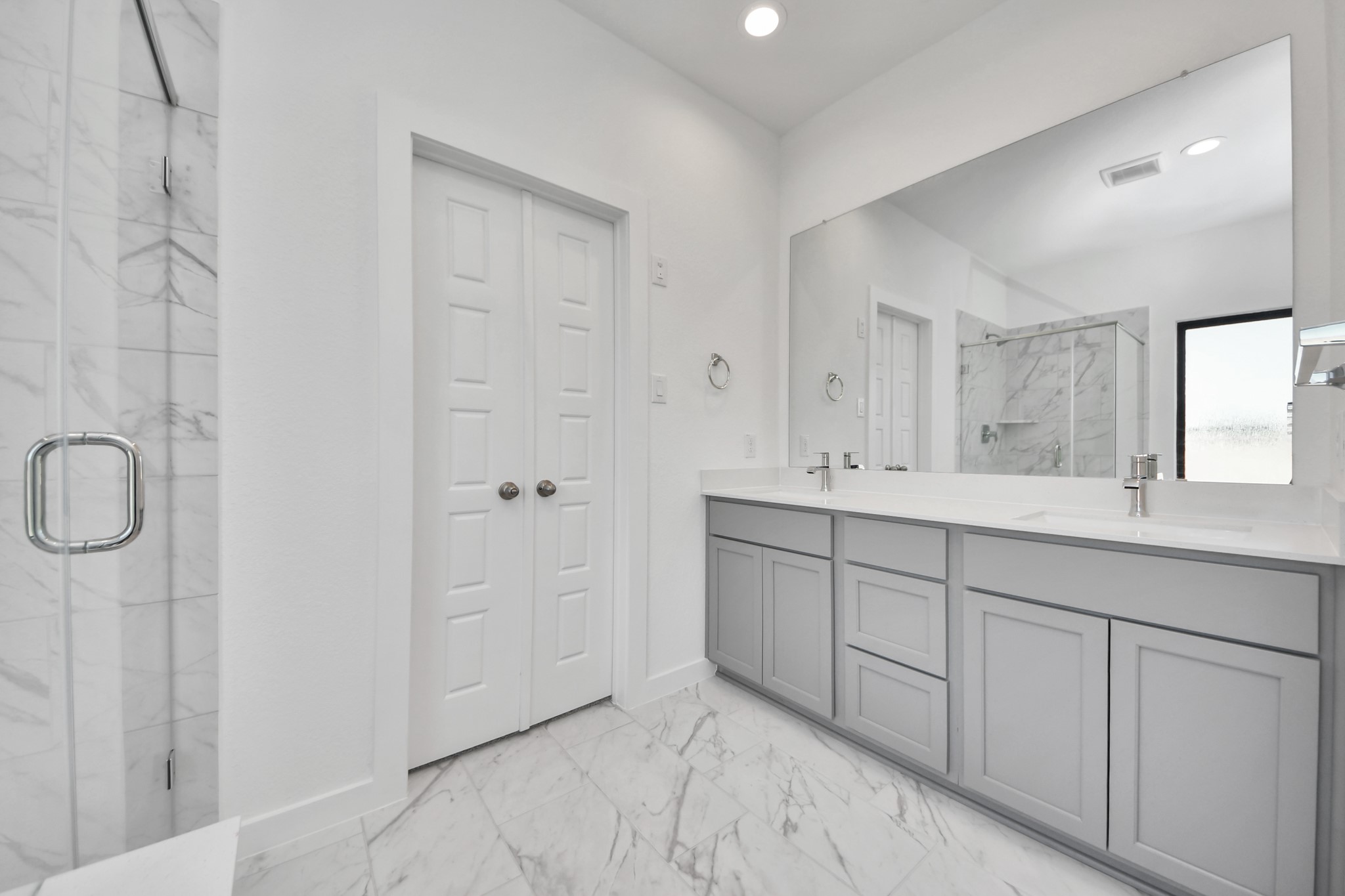 Elevate your daily routine at the elegant vanity, now equipped with double sinks, light countertops, modern hardware, and beautiful recessed lights.