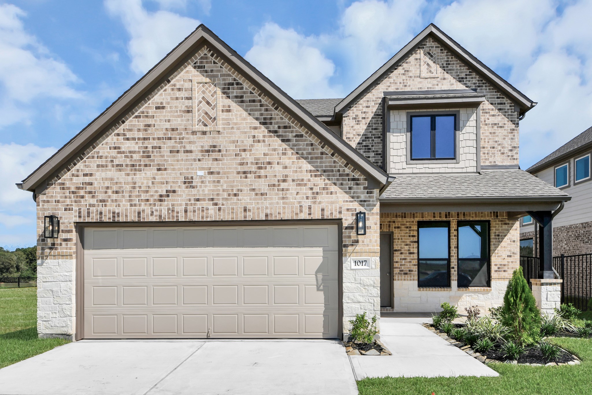 Meticulously maintained yard and lush landscape, paired with a premium elevation featuring captivating brick accents. Modern coach lights add a touch of contemporary elegance to the exterior.