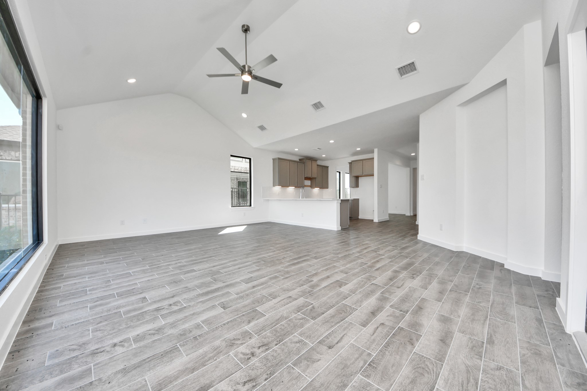Family room flooded with natural light through the expansive windows.  The premium tile flooring adds a touch of luxury to the space, creating the perfect setting for relaxing moments and cherished gatherings with loved ones.