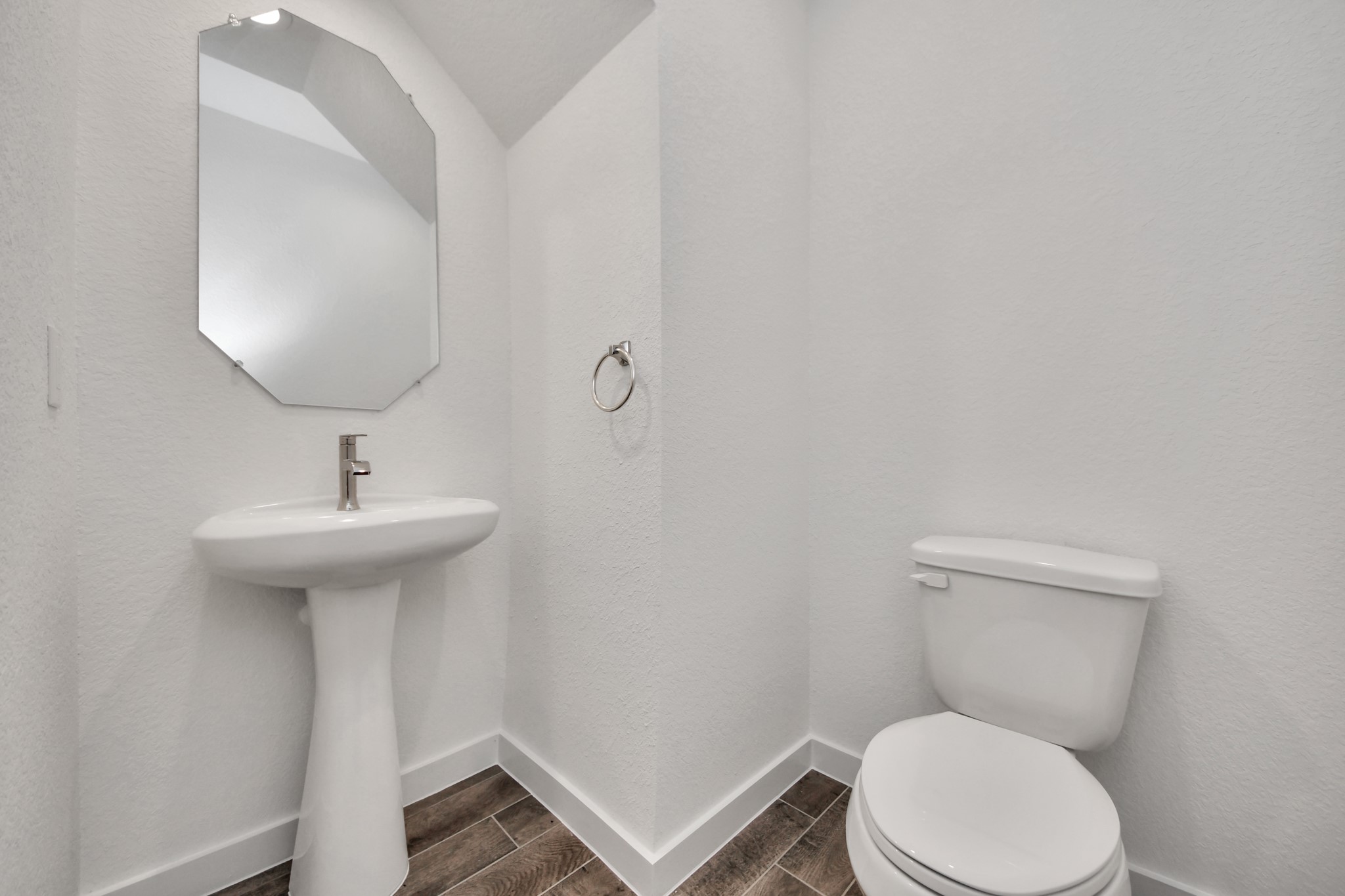 This half bathroom features a stylish pedestal sink, modern hardware, and bright recessed lighting, creating a sleek and inviting space.