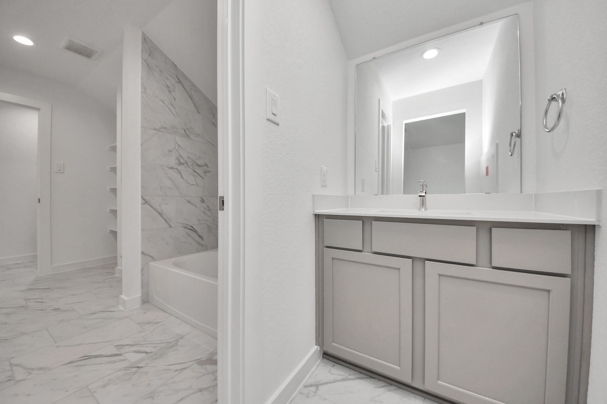 Experience convenience in the secondary bathroom, designed for Jack and Jill arrangements, now with a separate vanity area. This well-appointed space showcases stylish tile flooring, a bath/shower combo with an elegant tile surround, and light-stained wood cabinets. The beautiful light countertop adds a touch of sophistication, combining functionality and aesthetics seamlessly.