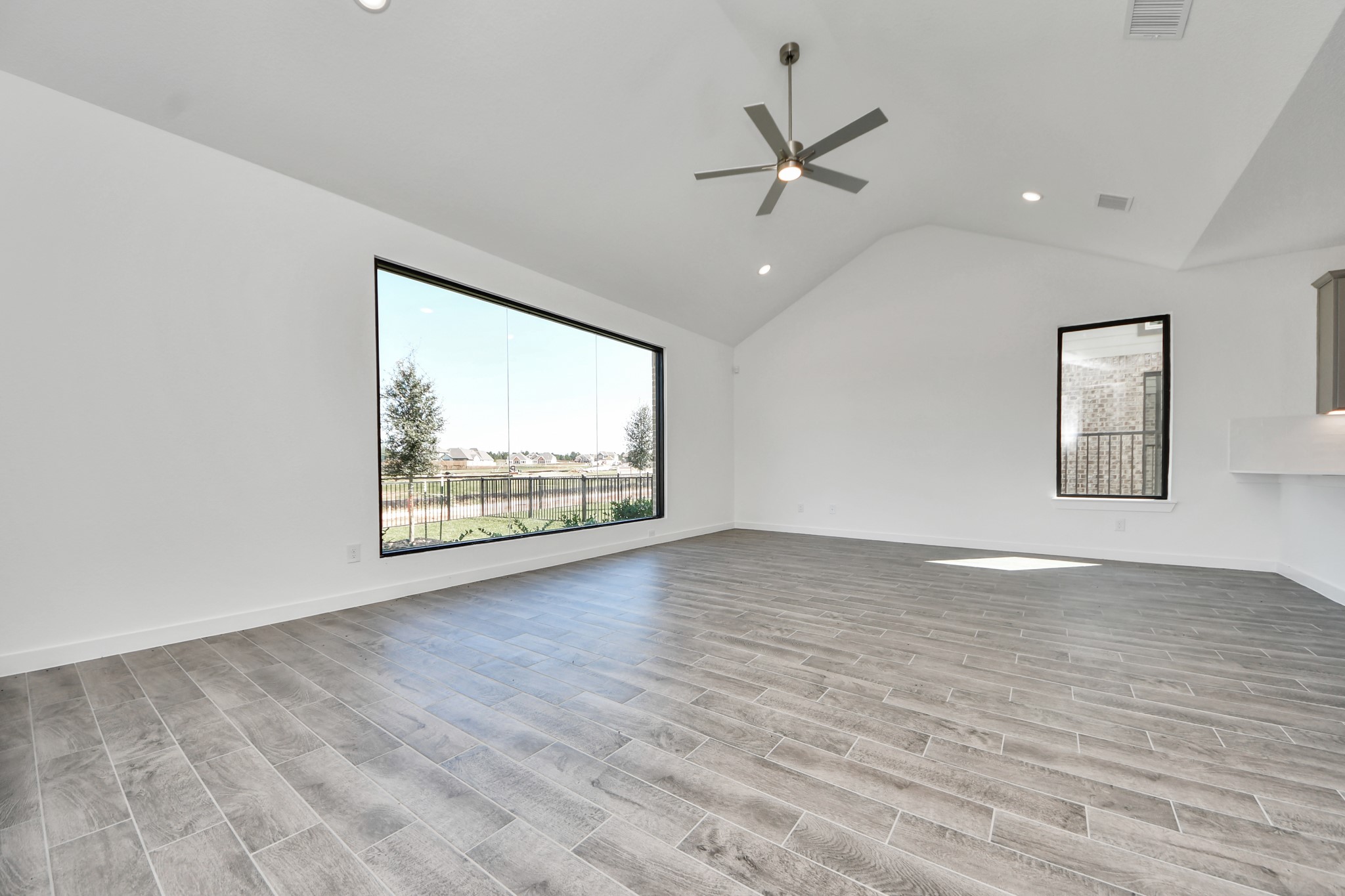 Relax and unwind in this inviting family room, illuminated by abundant natural light streaming in through tall windows, complemented by high ceilings and stunning flooring. Stay comfortable year-round with the gentle breeze from the ceiling fan, creating the perfect atmosphere for family gatherings.