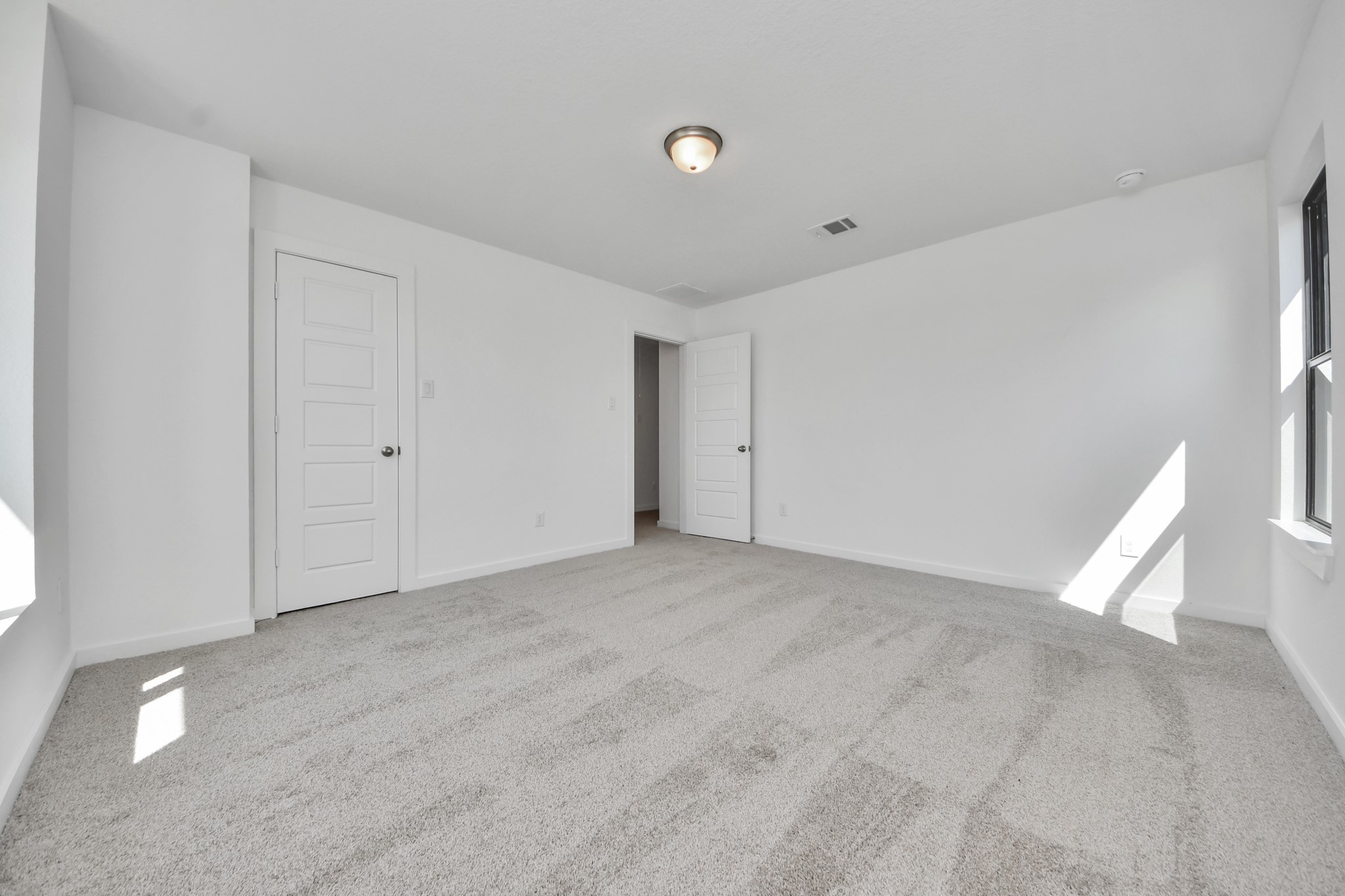 Secondary bedroom features plush carpeting, large windows that let in plenty of natural light, bright paint, and spacious closets.