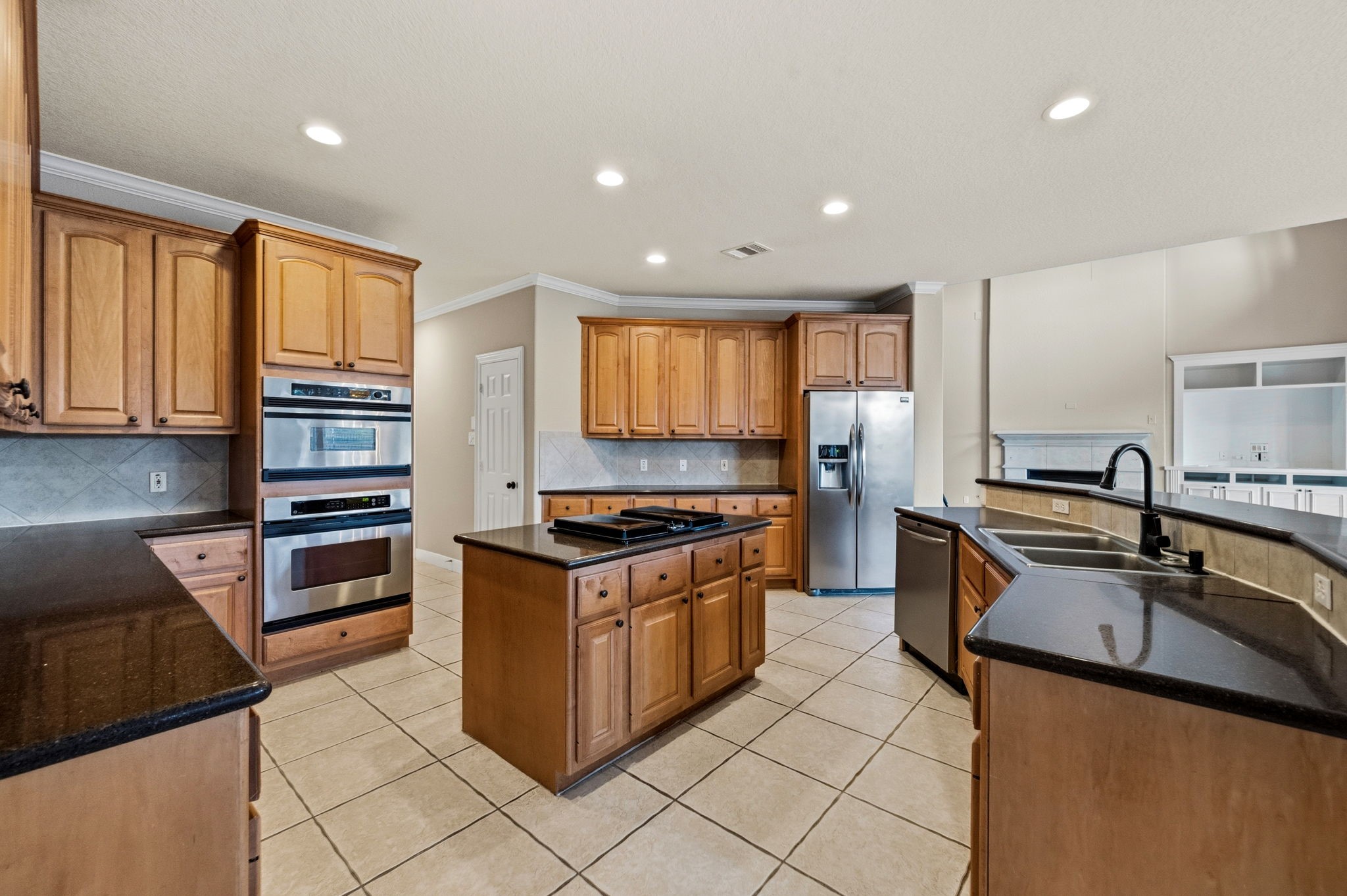 Spacious island kitchen with elegant wood cabinetry, granite countertops, and modern stainless steel appliances, featuring a convenient center island and ample storage.