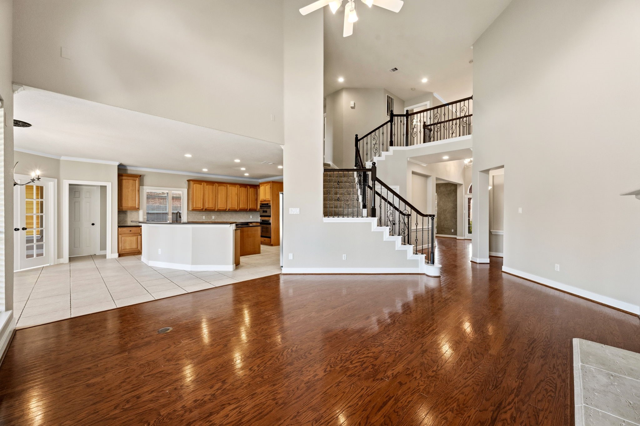 Spacious open-concept living area with elegant hardwood floors, a grand staircase, and a modern kitchen featuring ample cabinetry and a large island.