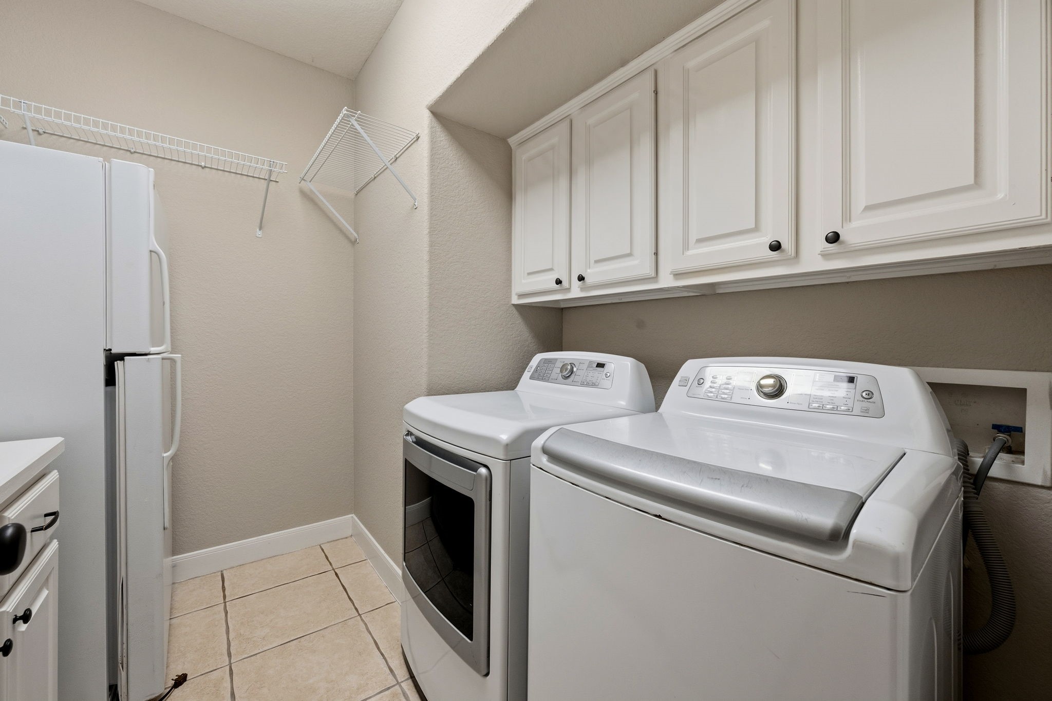 Spacious laundry room featuring modern appliances, ample cabinetry, and convenient shelving for organized storage.