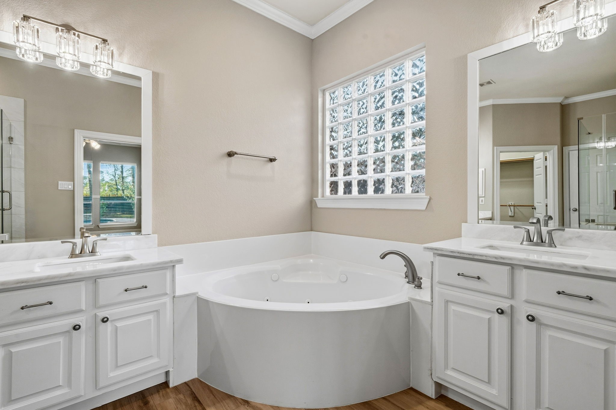 Elegant bathroom featuring a luxurious soaking tub, dual vanities with chic fixtures, and a large frosted window allowing natural light to flood the space.