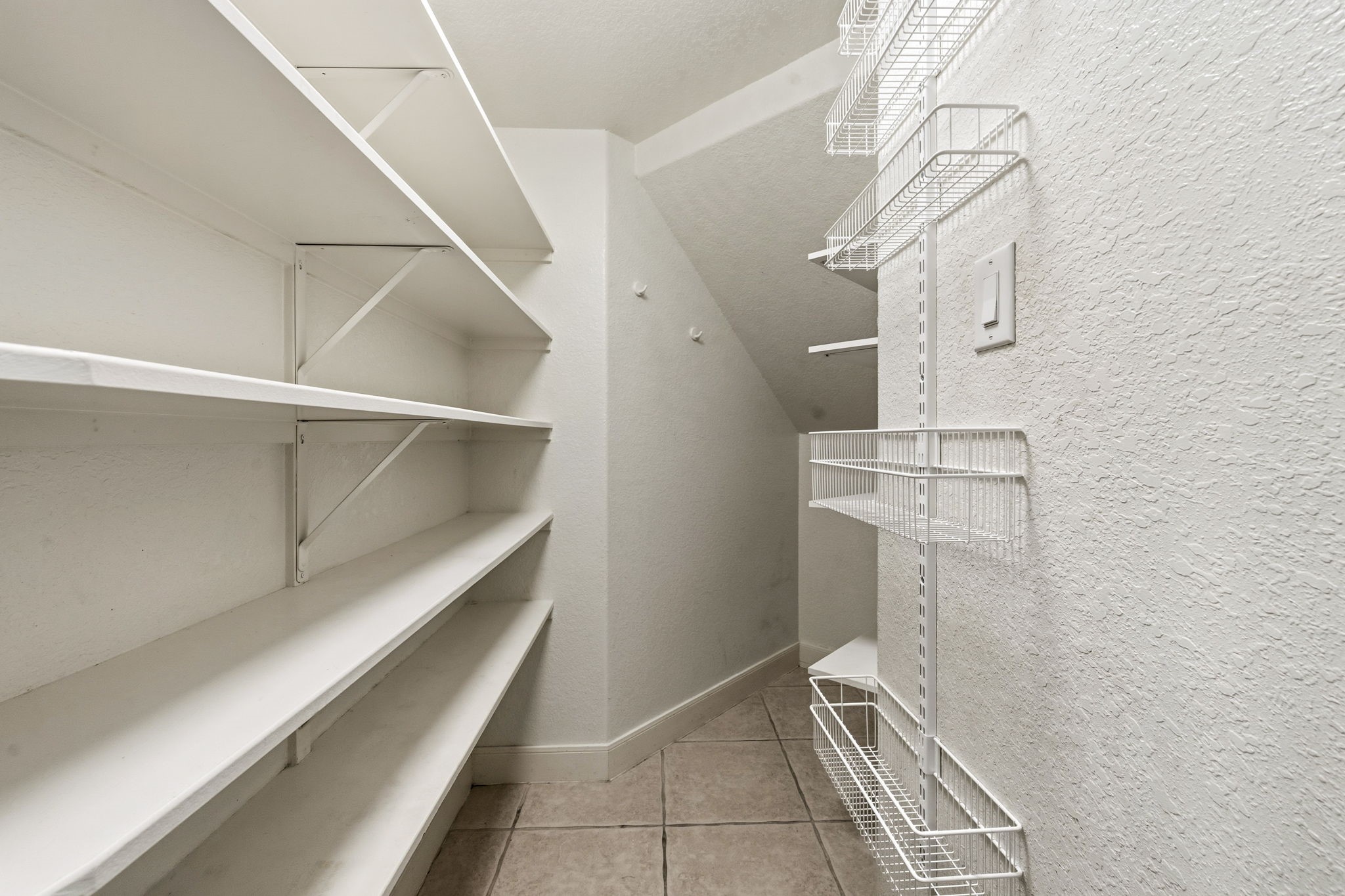Spacious pantry with ample shelving and wire racks, perfect for organized storage and easy access to essentials.
