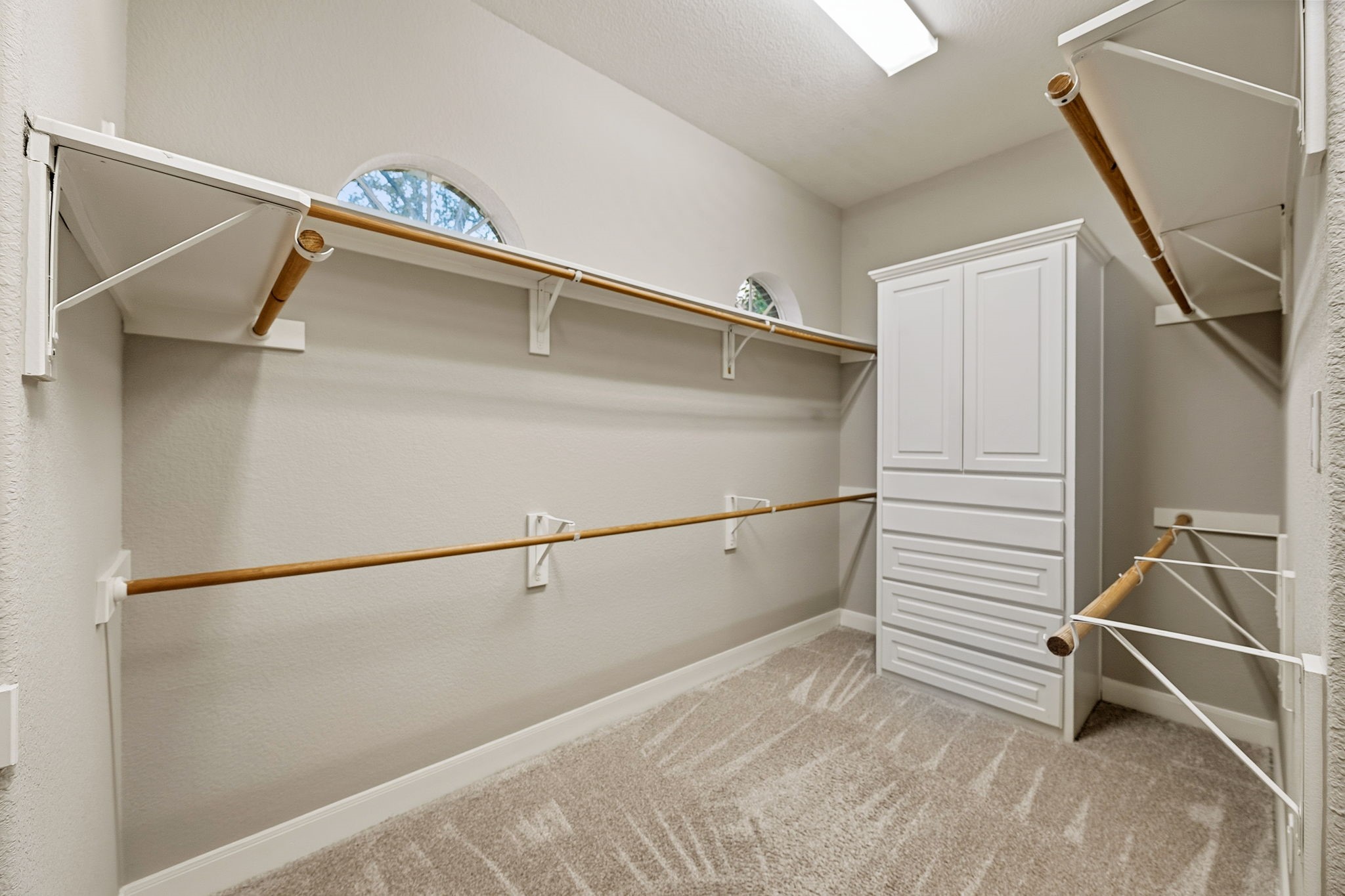 Spacious walk-in closet with ample shelving, hanging space, and a built-in storage unit, perfect for organizing your wardrobe.