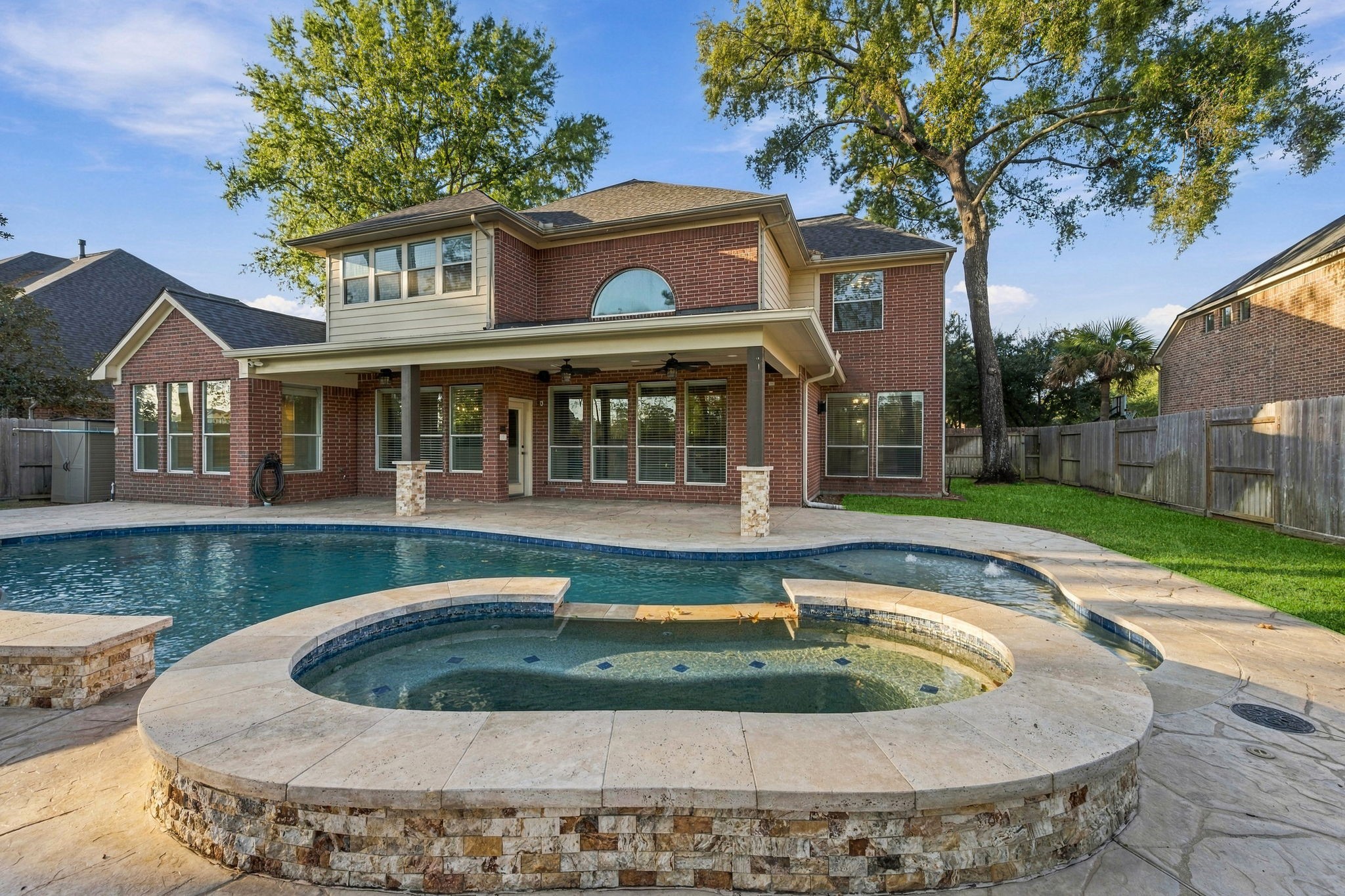 Stunning two-story brick home with a spacious backyard featuring a luxurious pool and spa, perfect for outdoor entertainment and relaxation.