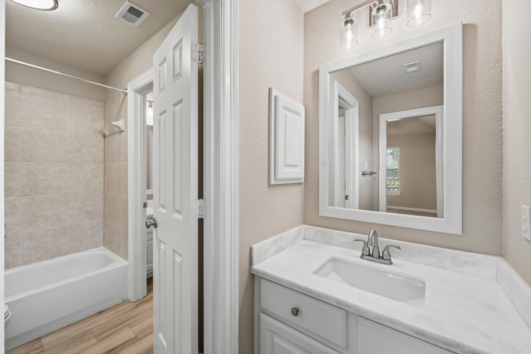 Elegant bathroom featuring a sleek vanity with updated countertop, modern fixtures, and a spacious tiled bathtub for a relaxing retreat.