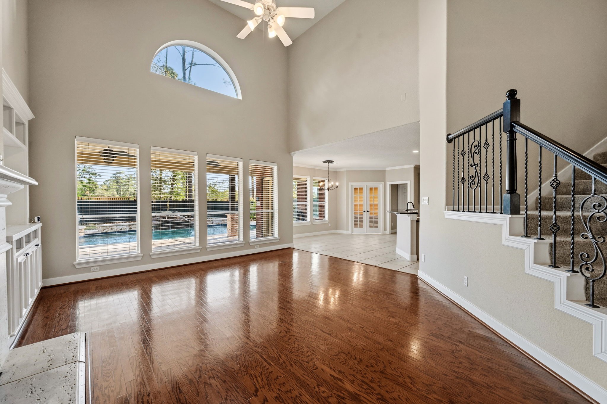 Spacious living area with high ceilings, elegant hardwood floors, and large windows offering a view of the pool. The open layout seamlessly connects to the kitchen and dining area, ideal for entertaining.