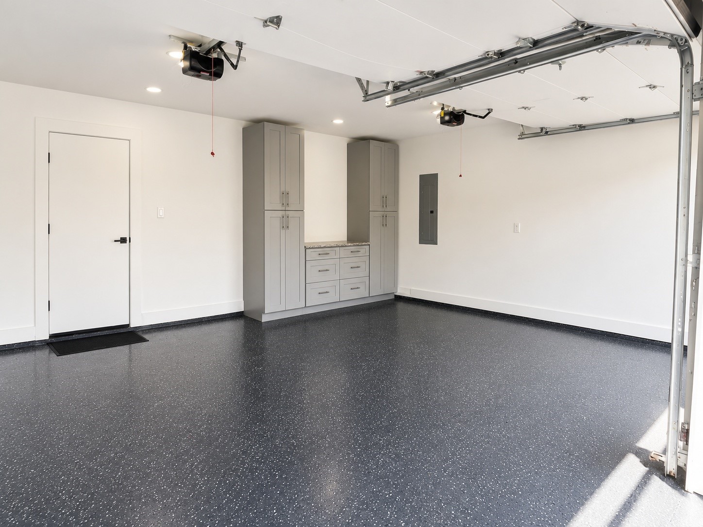 Oversized two-car garage with epoxy flooring, custom built-in storage, and plenty of room for vehicles and a workspace.