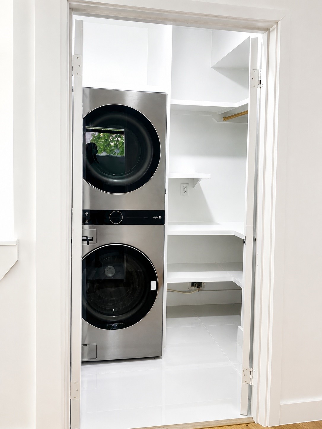Dedicated laundry room with built-in shelving and a full-size stacked washer and dryer.