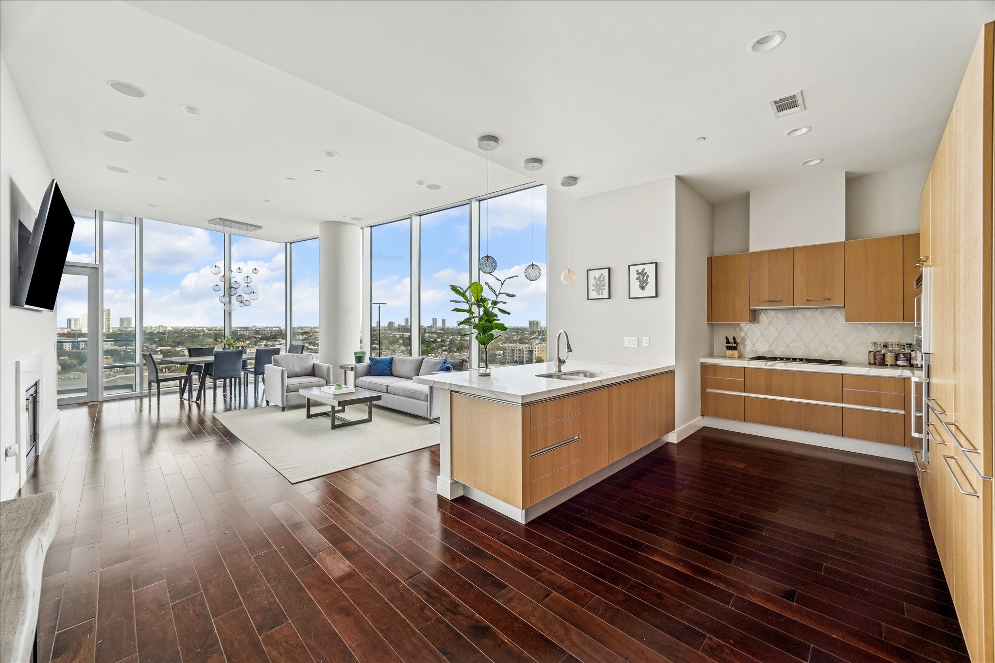 Contemporary kitchen with oversized island, quartz countertops, pendant lighting, and seamless flow to the living and dining areas framed by floor-to-ceiling windows.