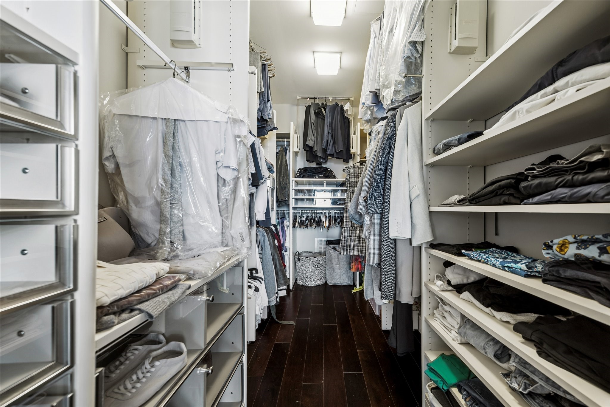 Custom walk-in closet with built-in shelving, drawer storage, hanging space, and hardwood flooring.