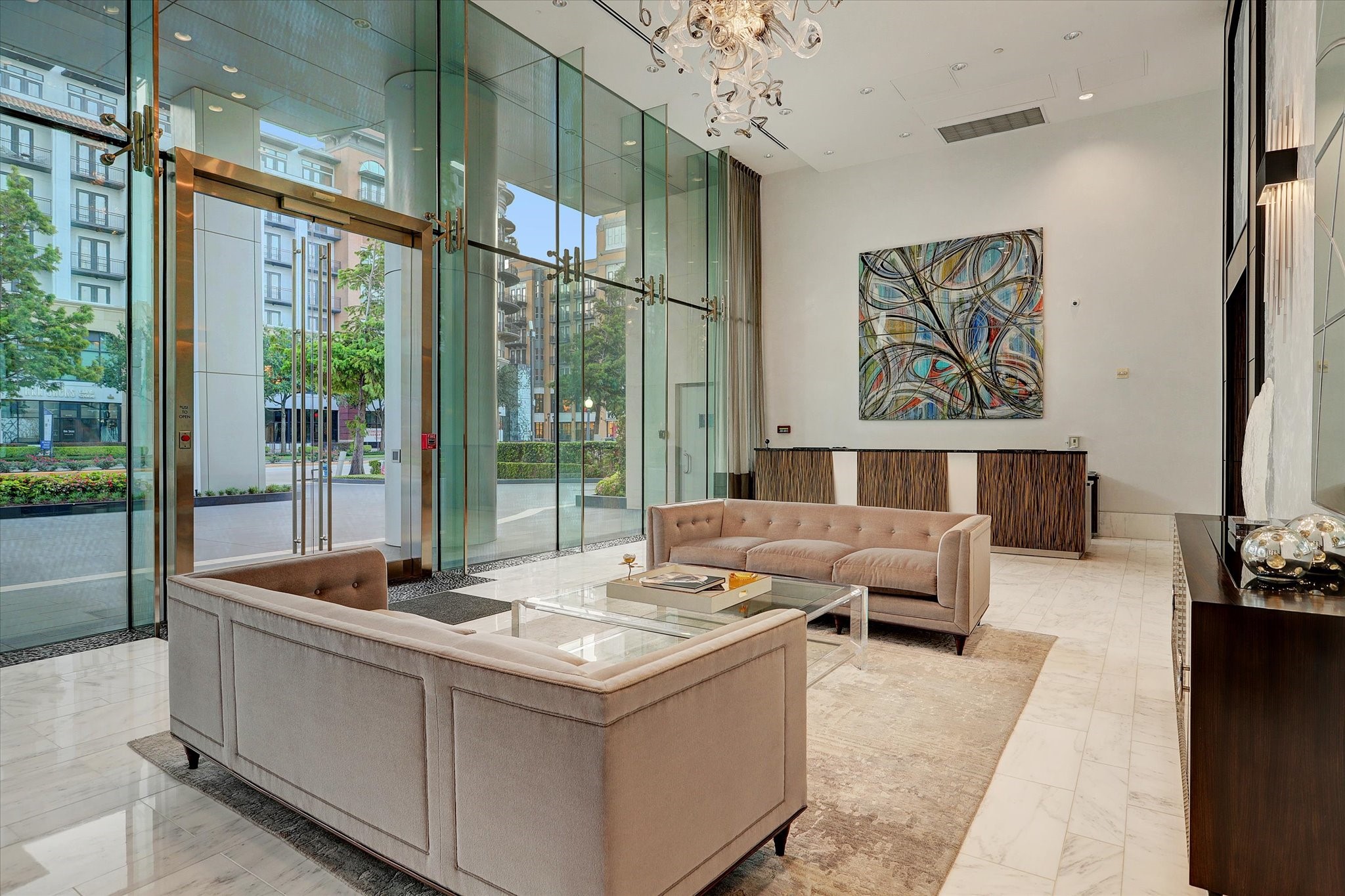 Elegant lobby with soaring glass walls, marble flooring, chandelier lighting, and secure concierge entry.
