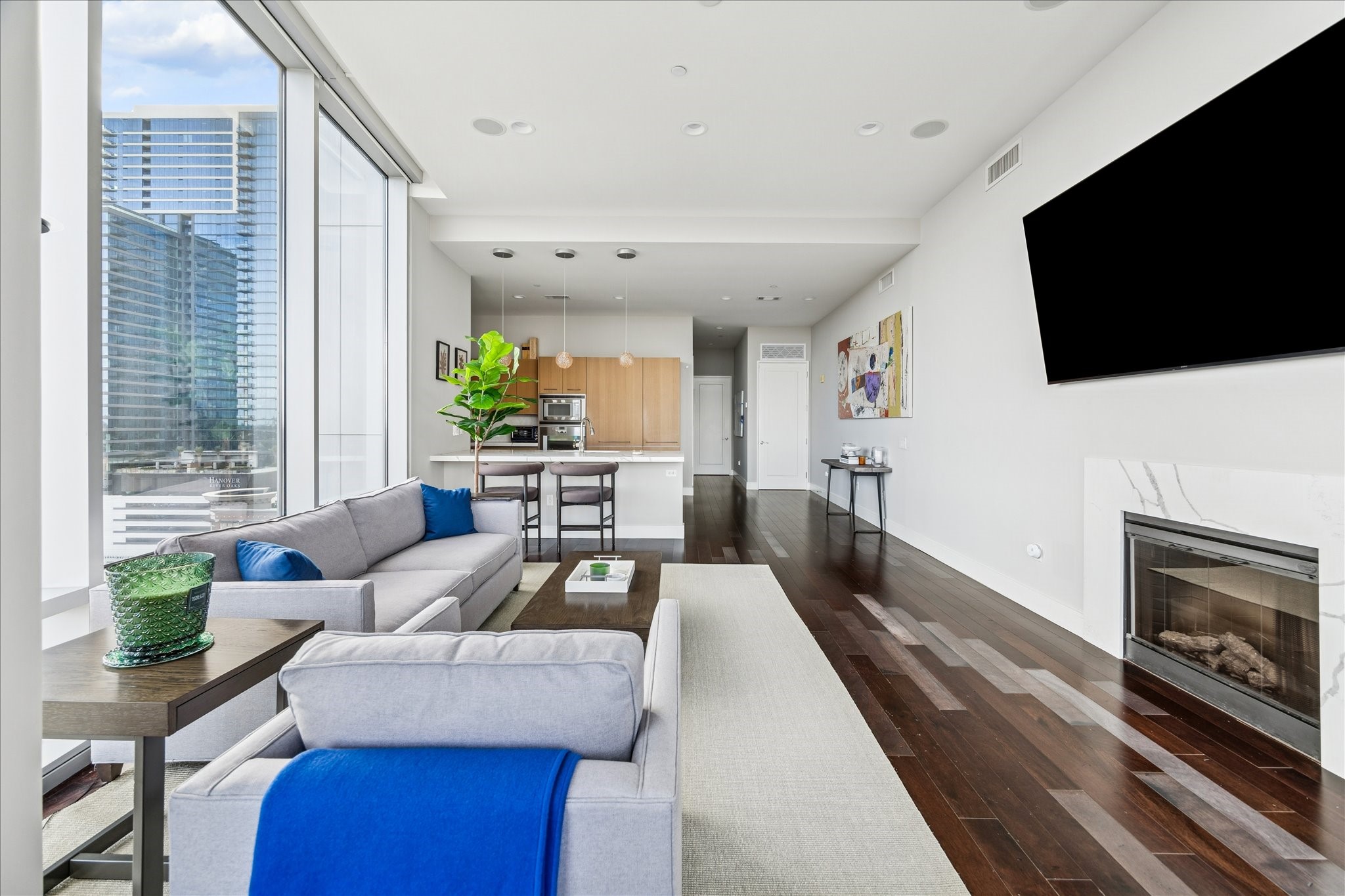 View from living area toward kitchen showing large island, pendant lighting, hardwood floors, and open sightlines.
