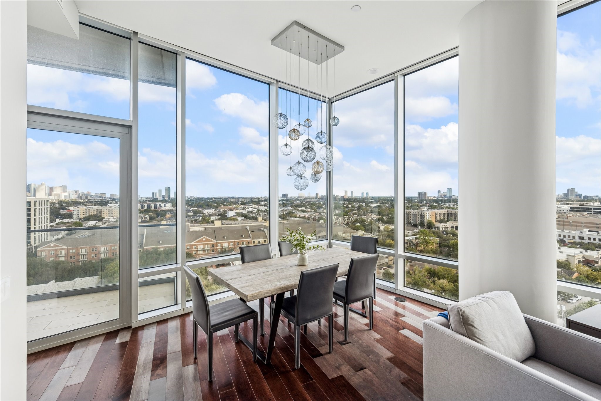 Corner dining space wrapped in floor-to-ceiling glass with skyline views and terrace access.
