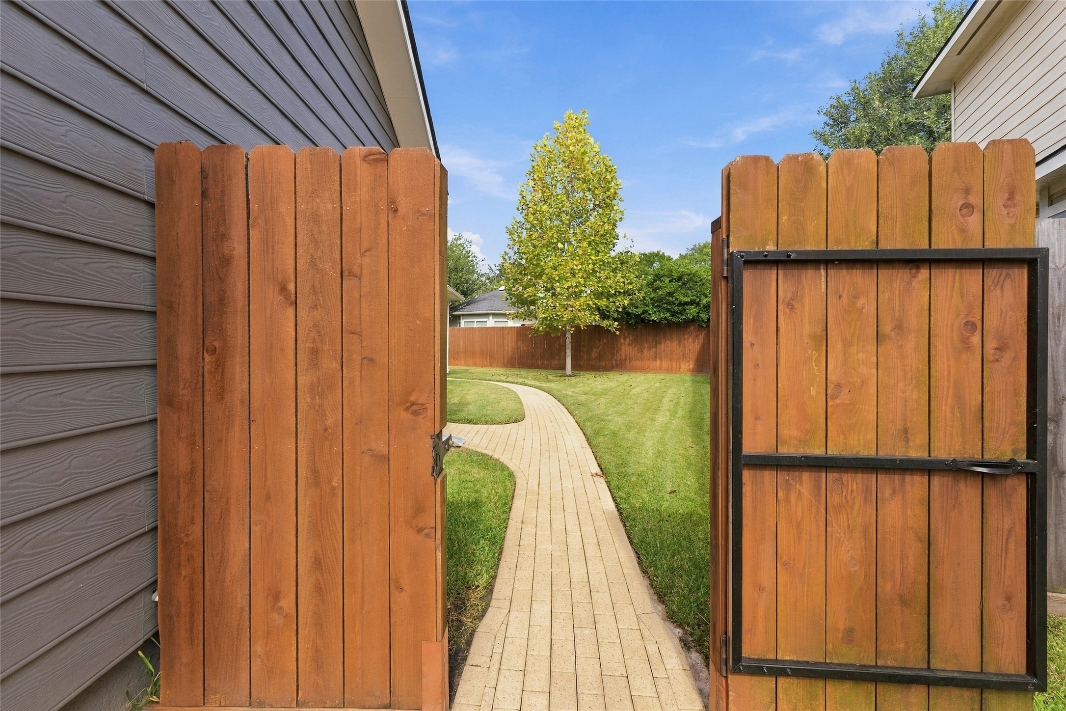 Brick walkway leads to a gorgeous backyard.