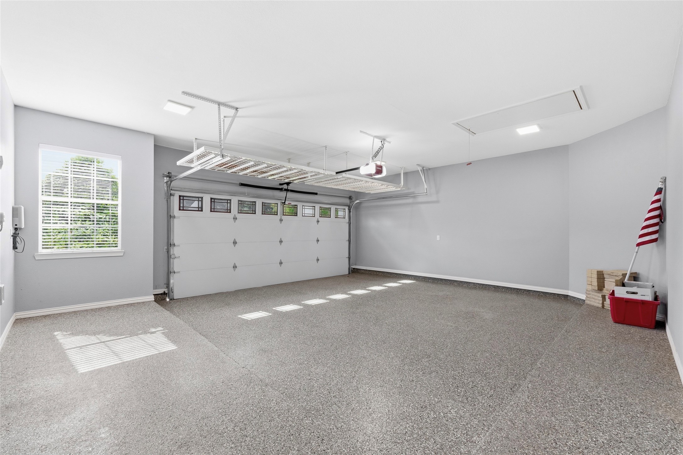 Spacious garage with a 5' extension, insulated garage door, accent windows, overhead storage, and Epoxy coating.
