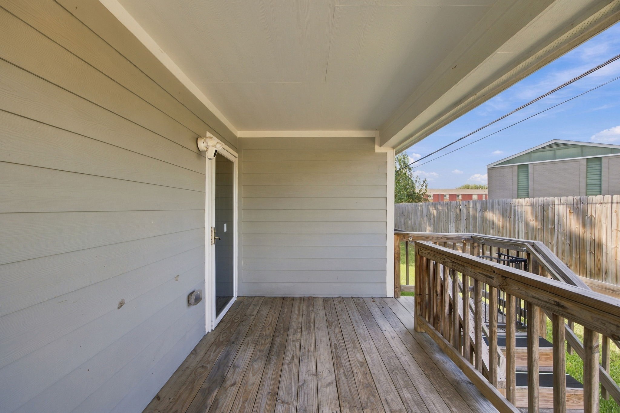Covered back porch featuring a wooden deck, privacy fencing, and space to enjoy the outdoors.