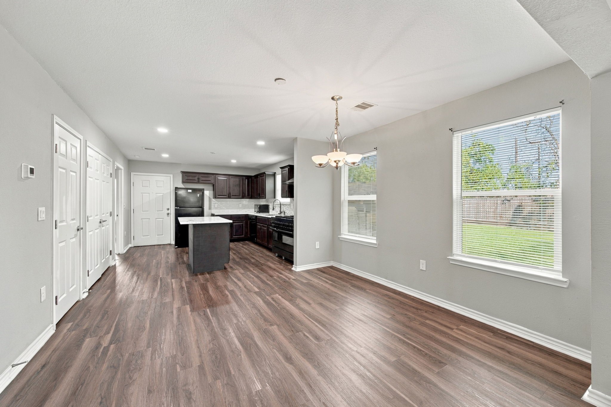 Open living and kitchen area featuring wood-look flooring, recessed lighting, and a functional layout.